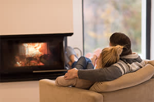 couple sitting in front of fireplace at home