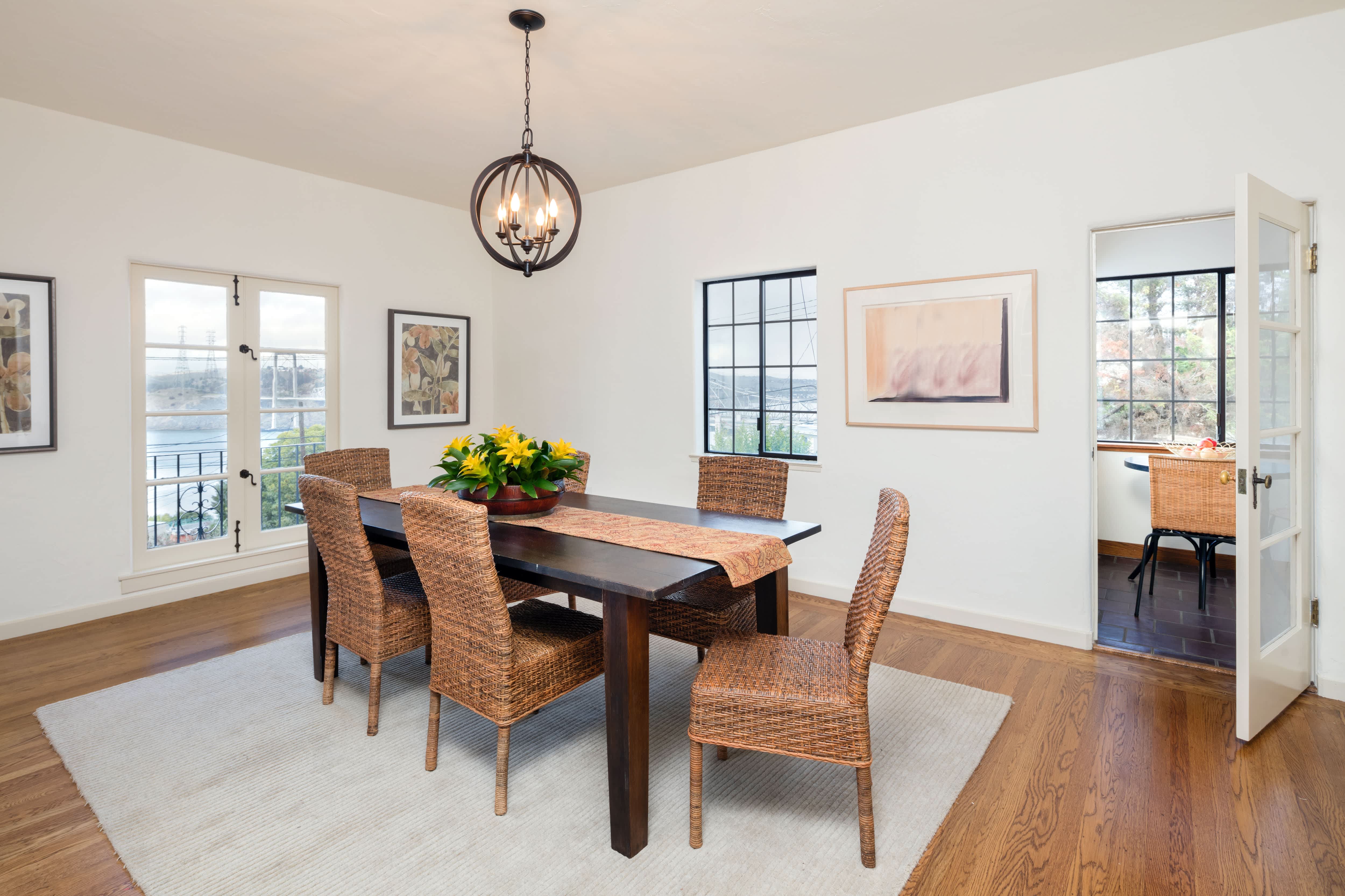 Dining room with wood dining table, rattan chairs, and circular modern farmhouse iron chandelier