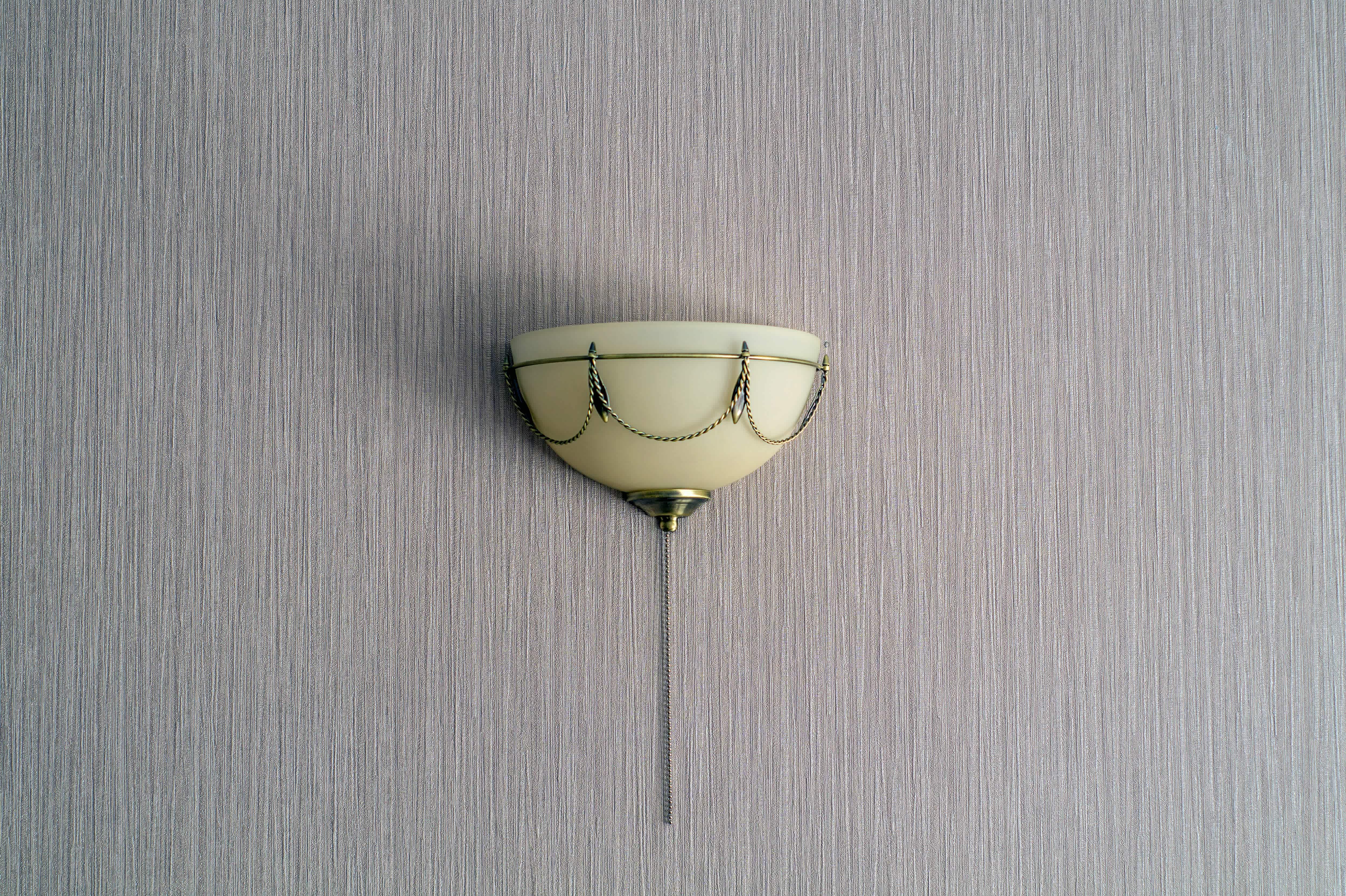 A decorative half-moon wall sconce on a gray wall