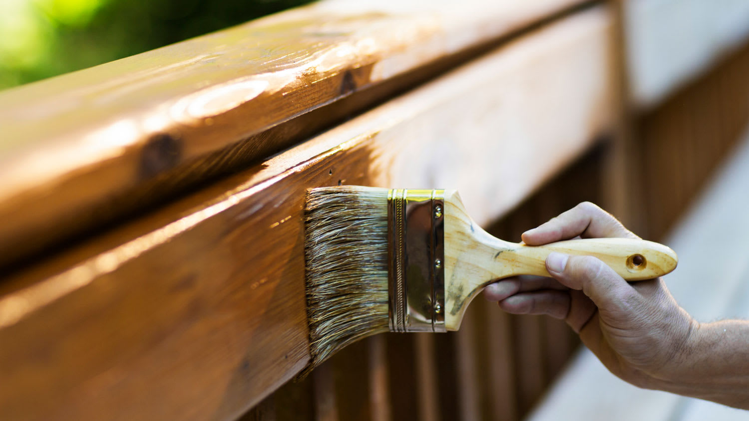 A hand applying varnish to wooden furniture