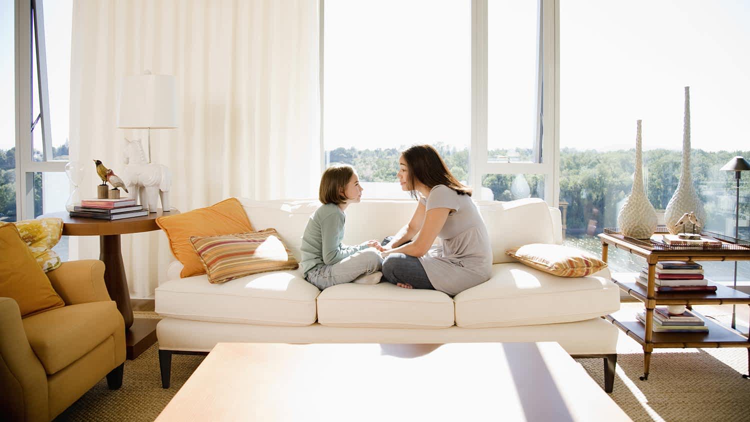 A mother sitting on a sofa with her daughter on a sunny day