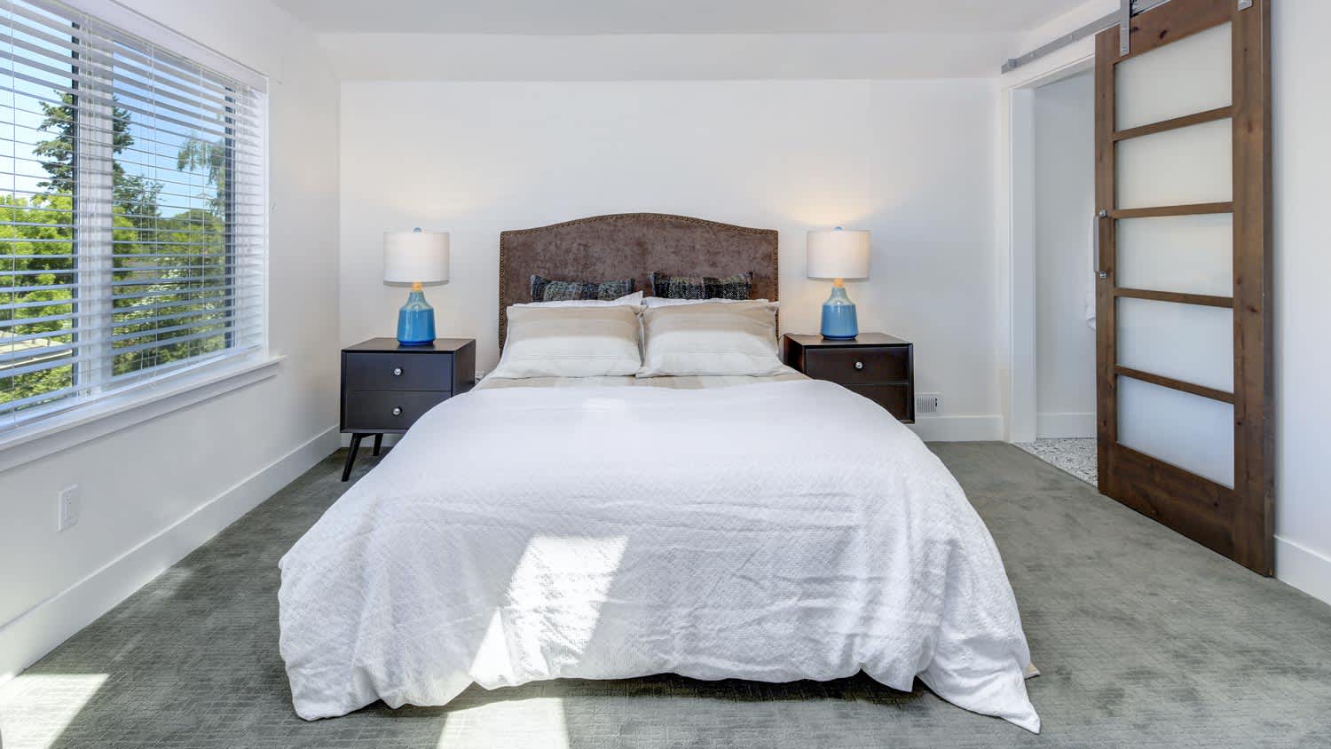 A beautiful master bedroom with a barn door leading to en-suite bathroom