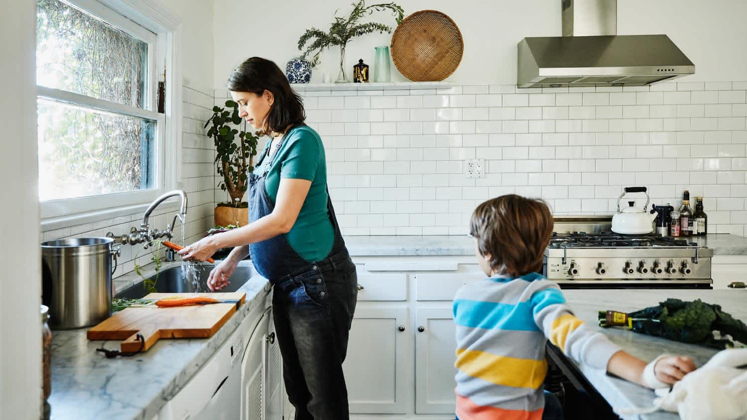 Pregnant mother washing vegetables at sink