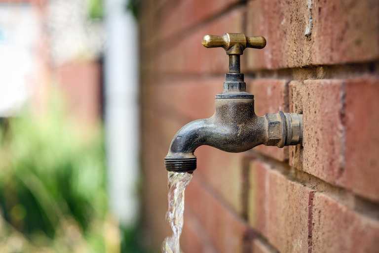 closeup of outdoor faucet against brick wall