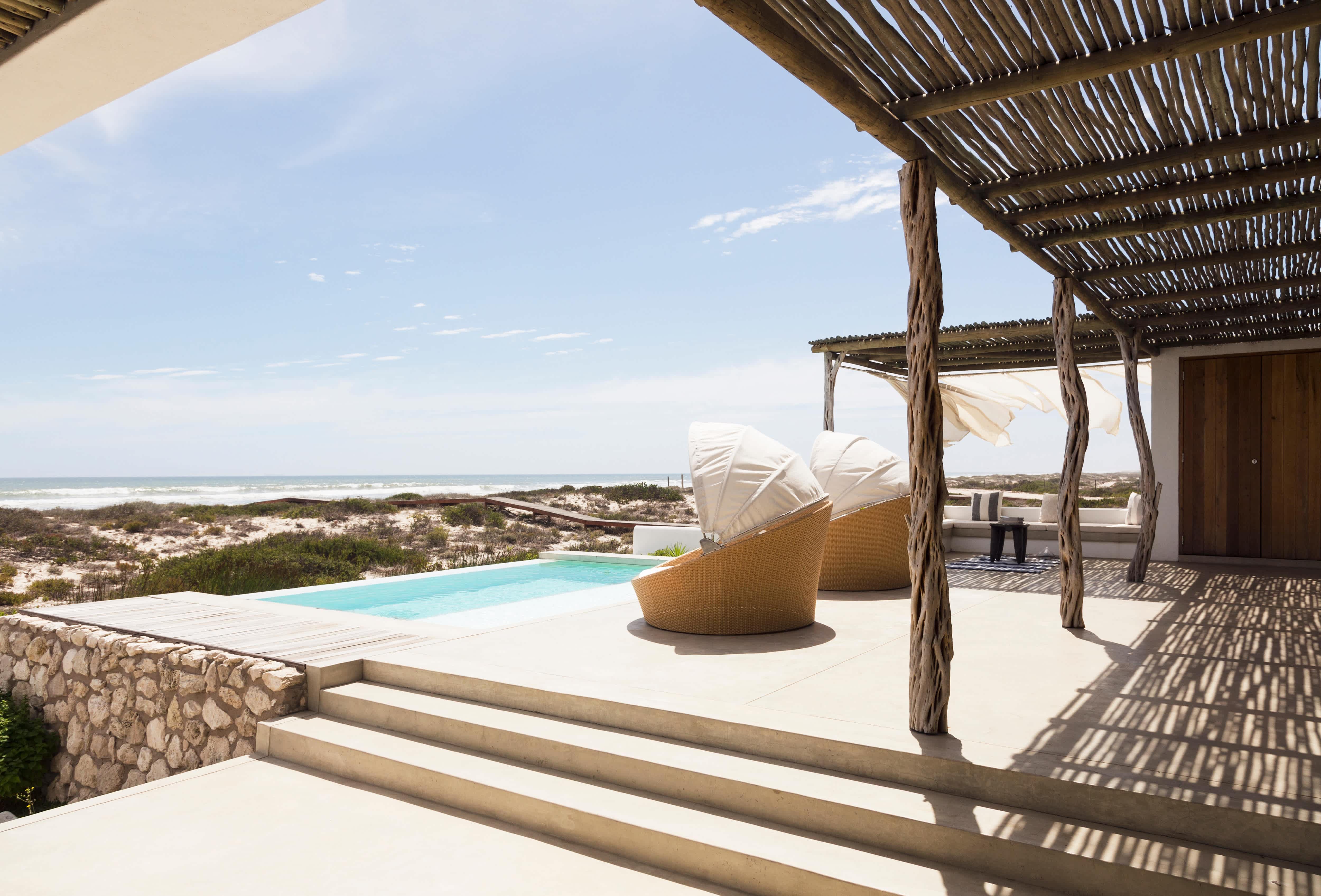 A reclaimed wood patio near the beach with a pool and covered deck chairs