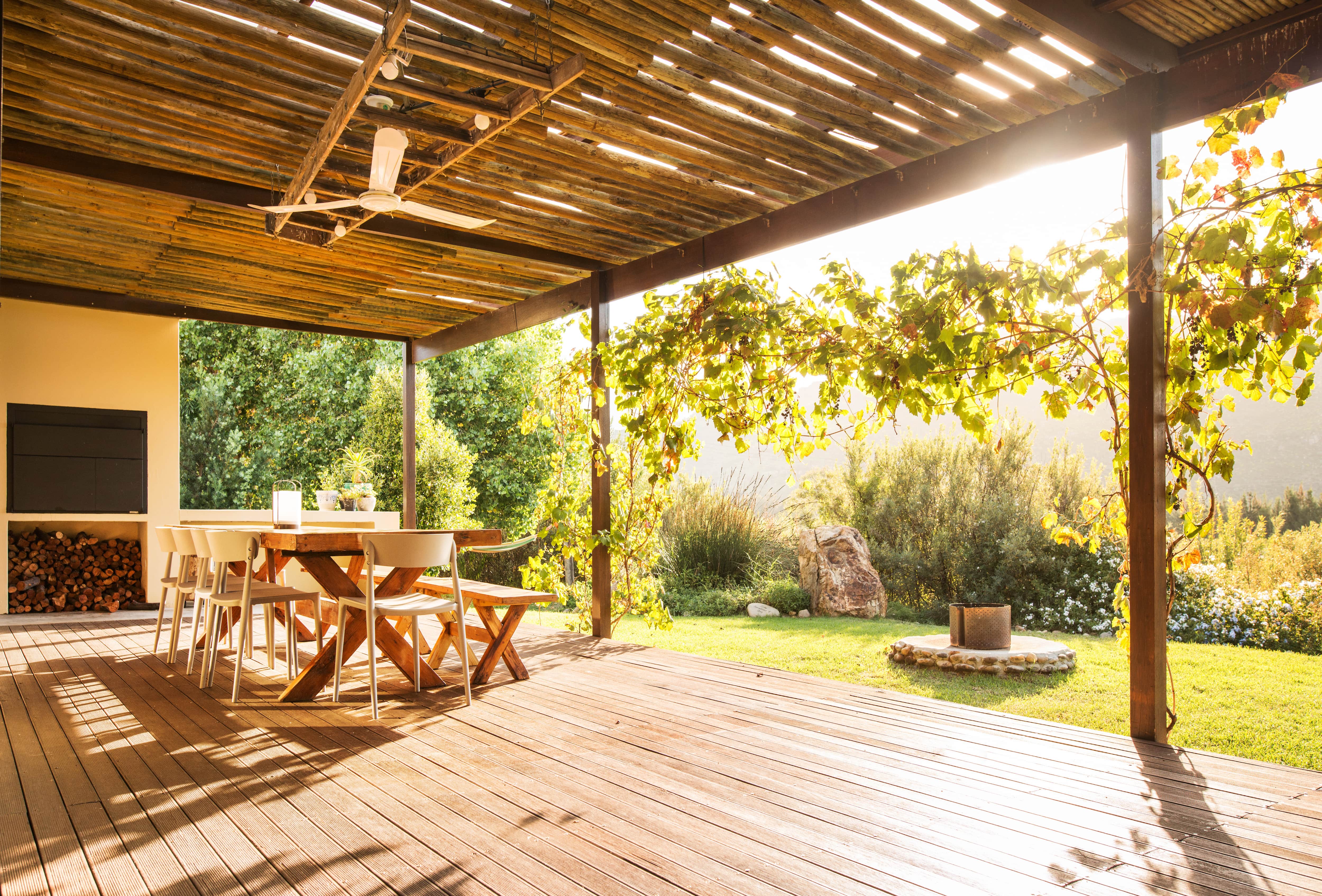 A rustic outdoor patio with exposed beams and a ceiling fan