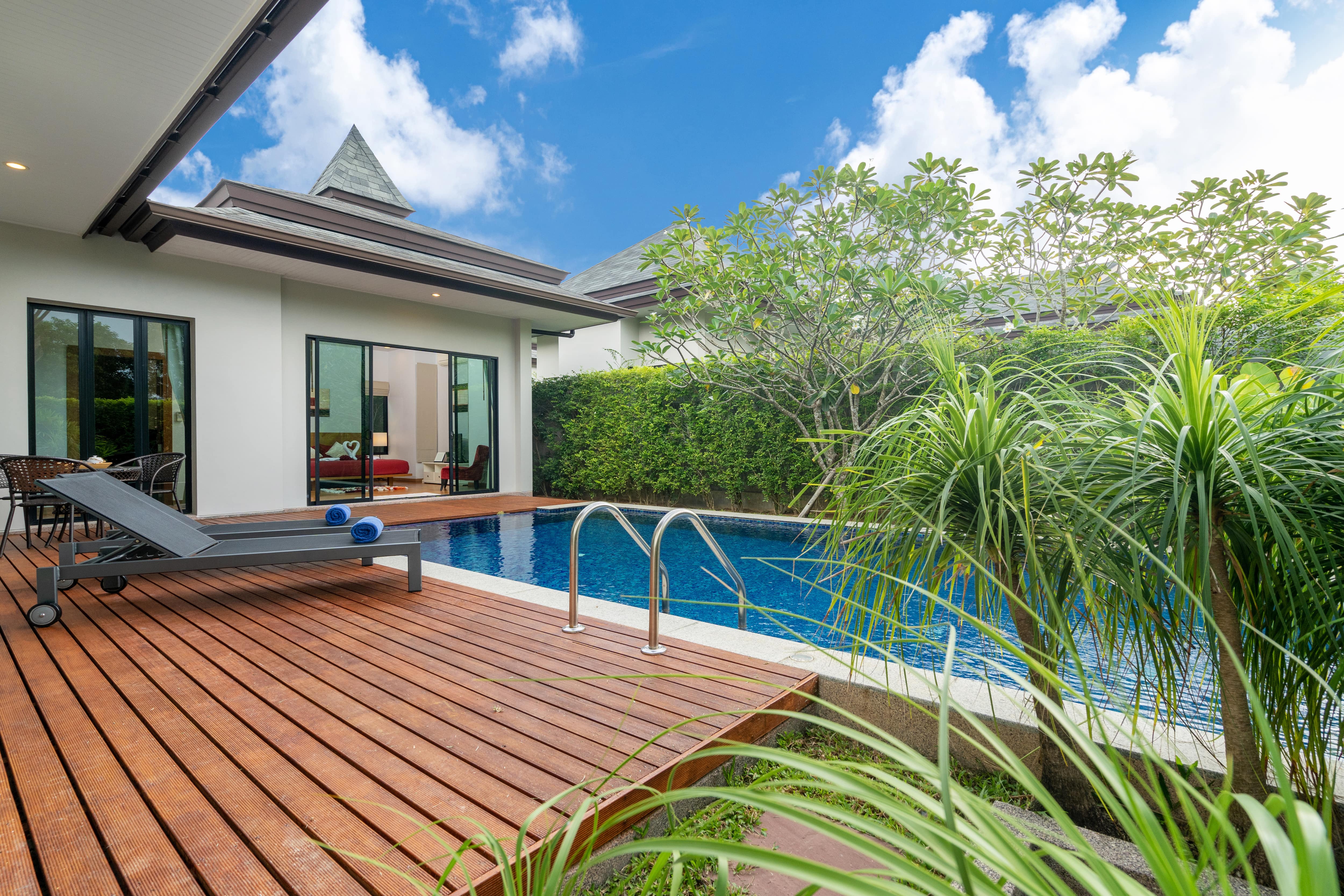 A picture of a house with a swimming pool and deck chairs