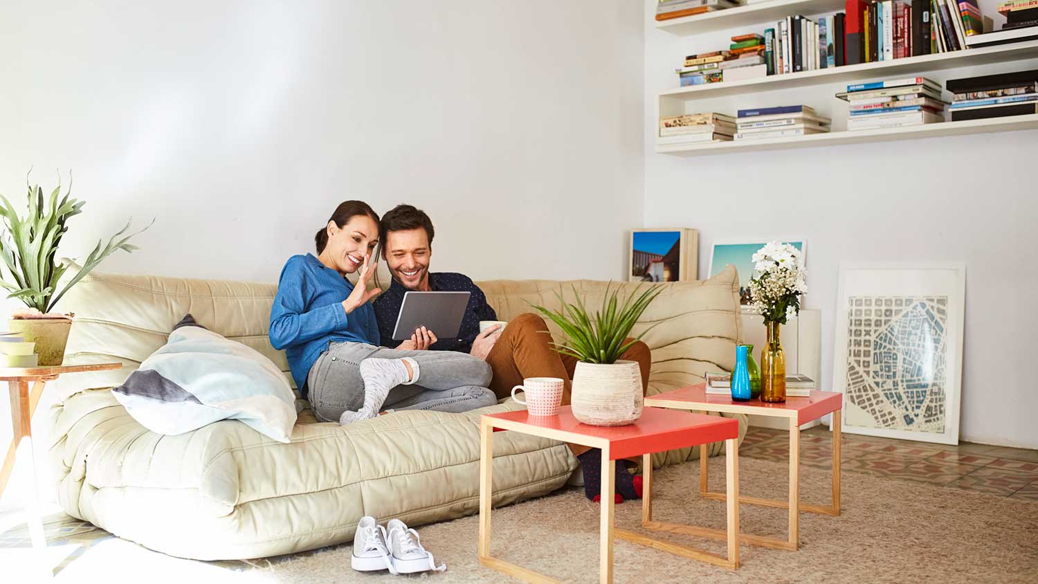 Couple sitting on the sofa using tablet for a video conference