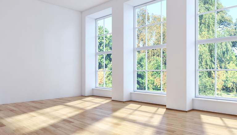 three sunny windows of an empty room overlooking trees