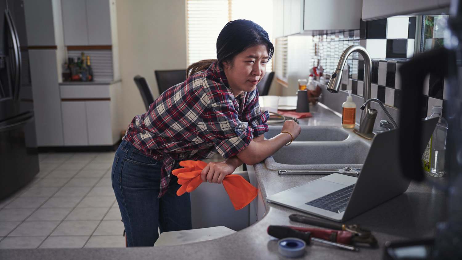 A woman repairing her kitchen faucet