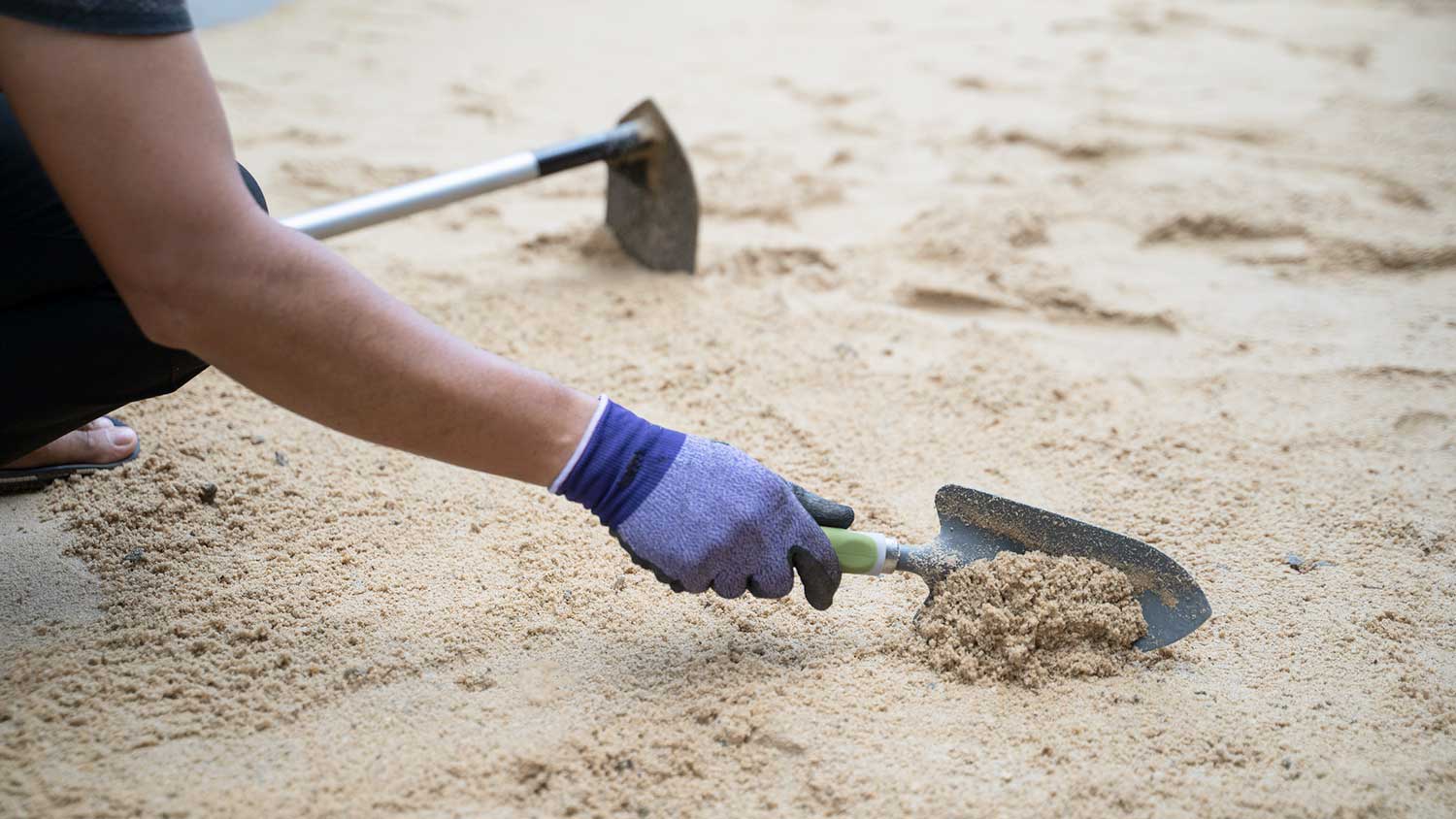 Worker laying sand in the yard before pouring concrete