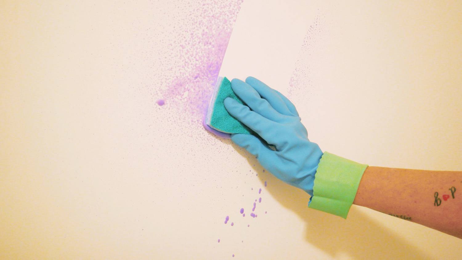 A woman’s hand in glove washing a wall