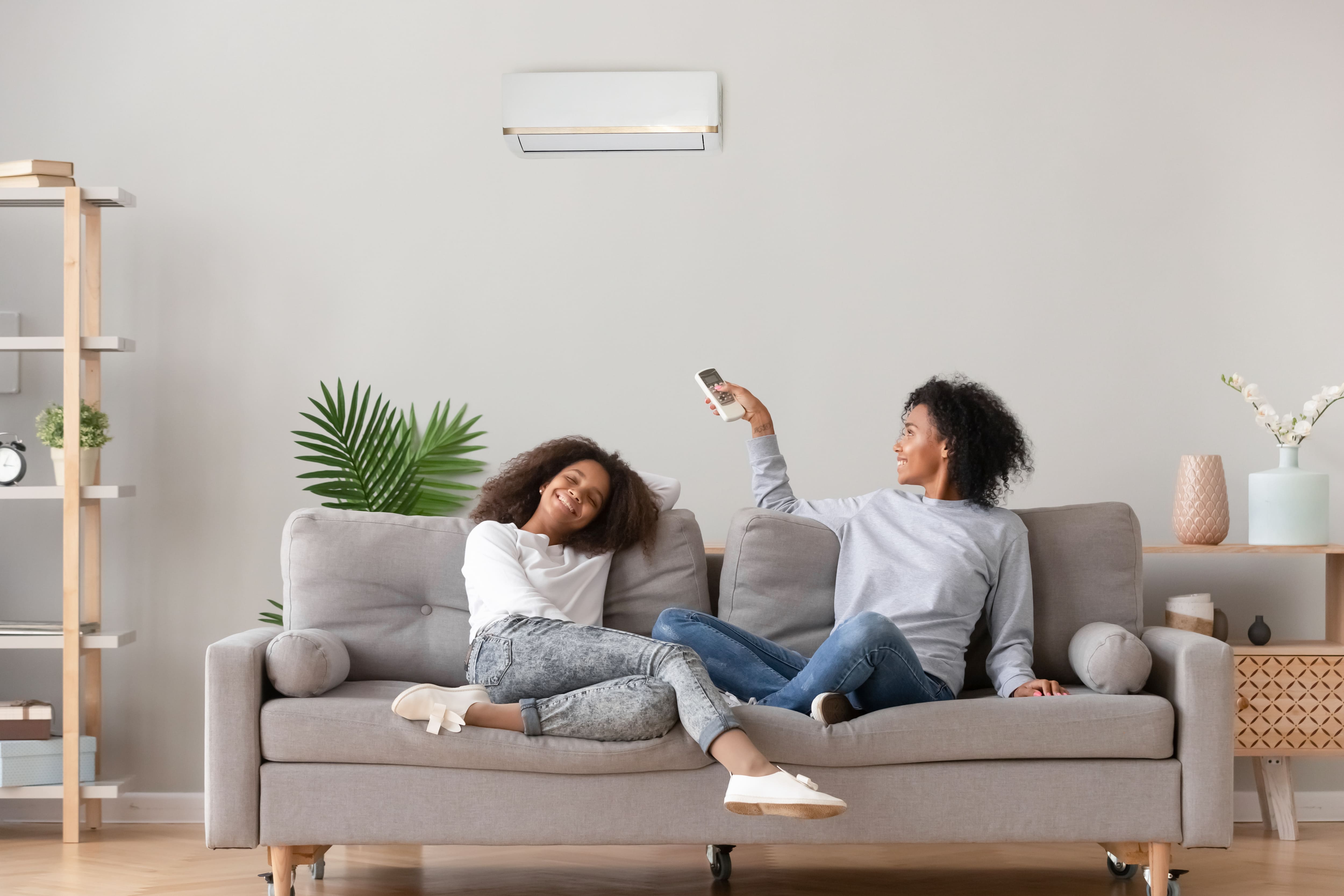 A woman and young girl relax on a couch enjoying the air conditioning