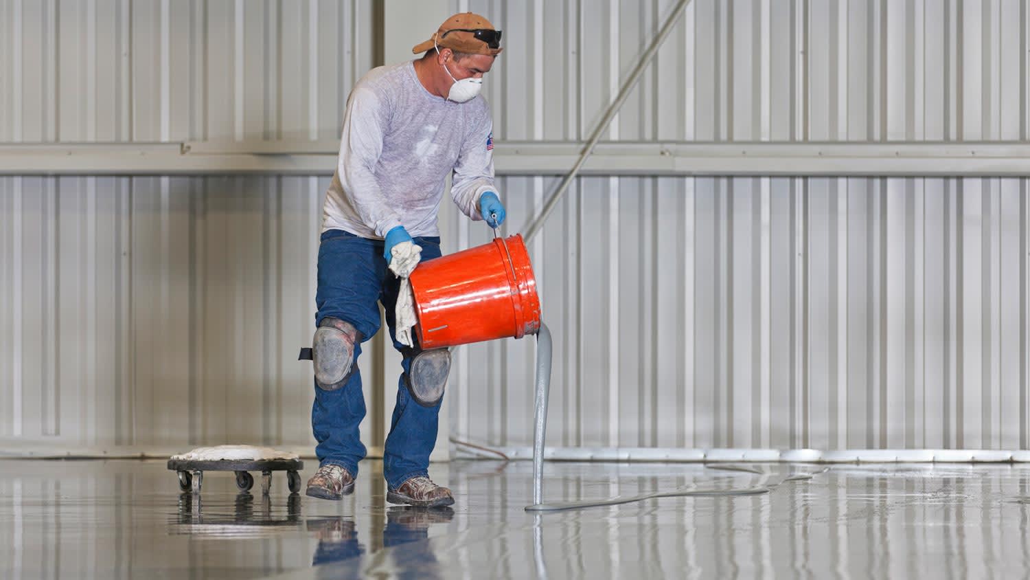 A worker pouring epoxy paint in a garage