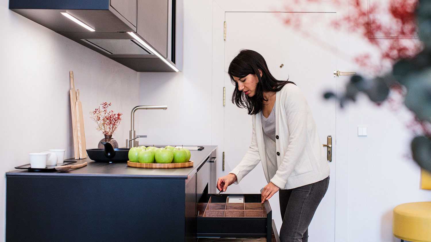Woman sorts through drawer in kitchen