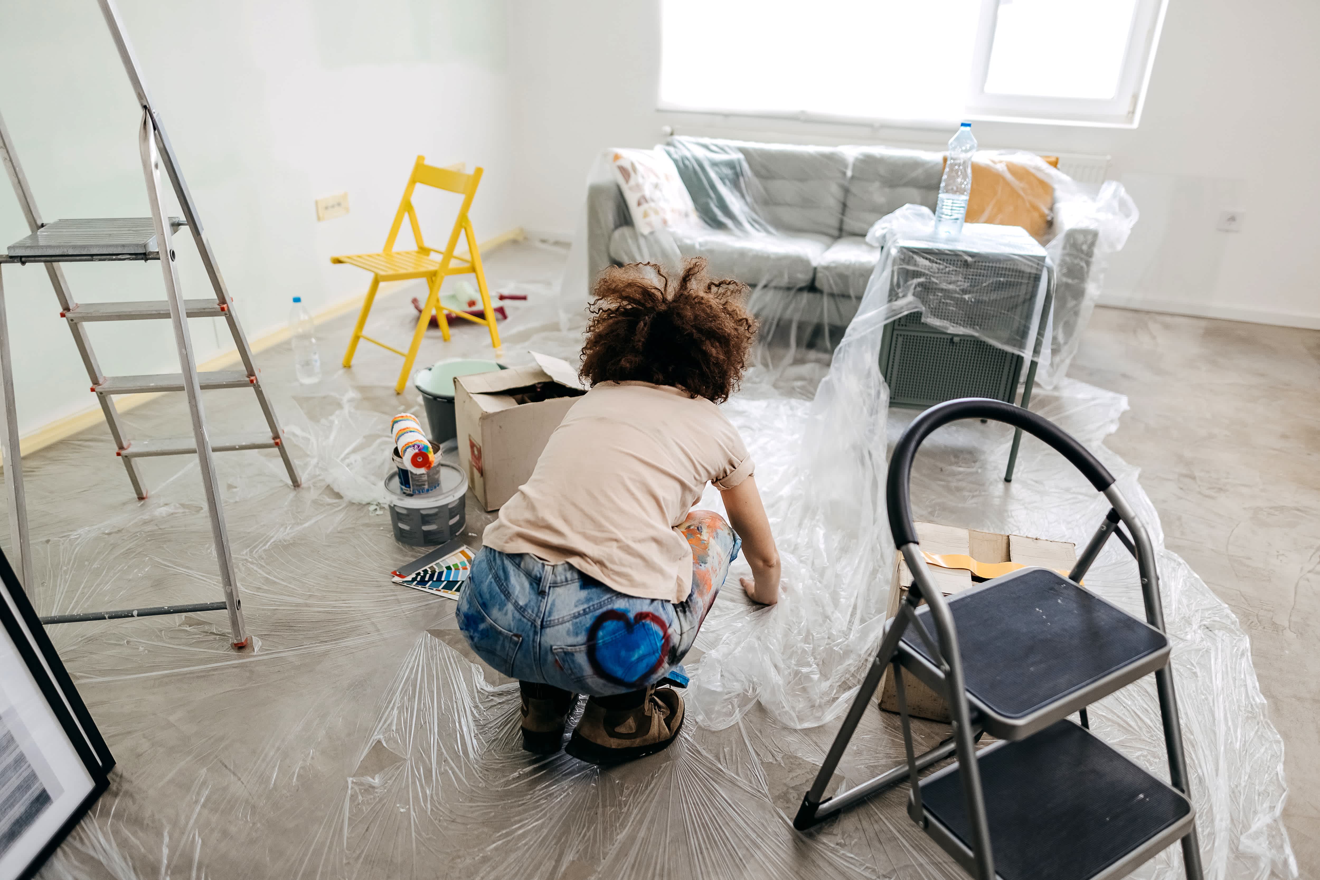 Woman covering floors and furniture with plastic before painting