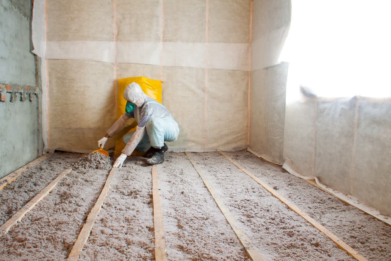 person adding cellulose insulation to floor of home