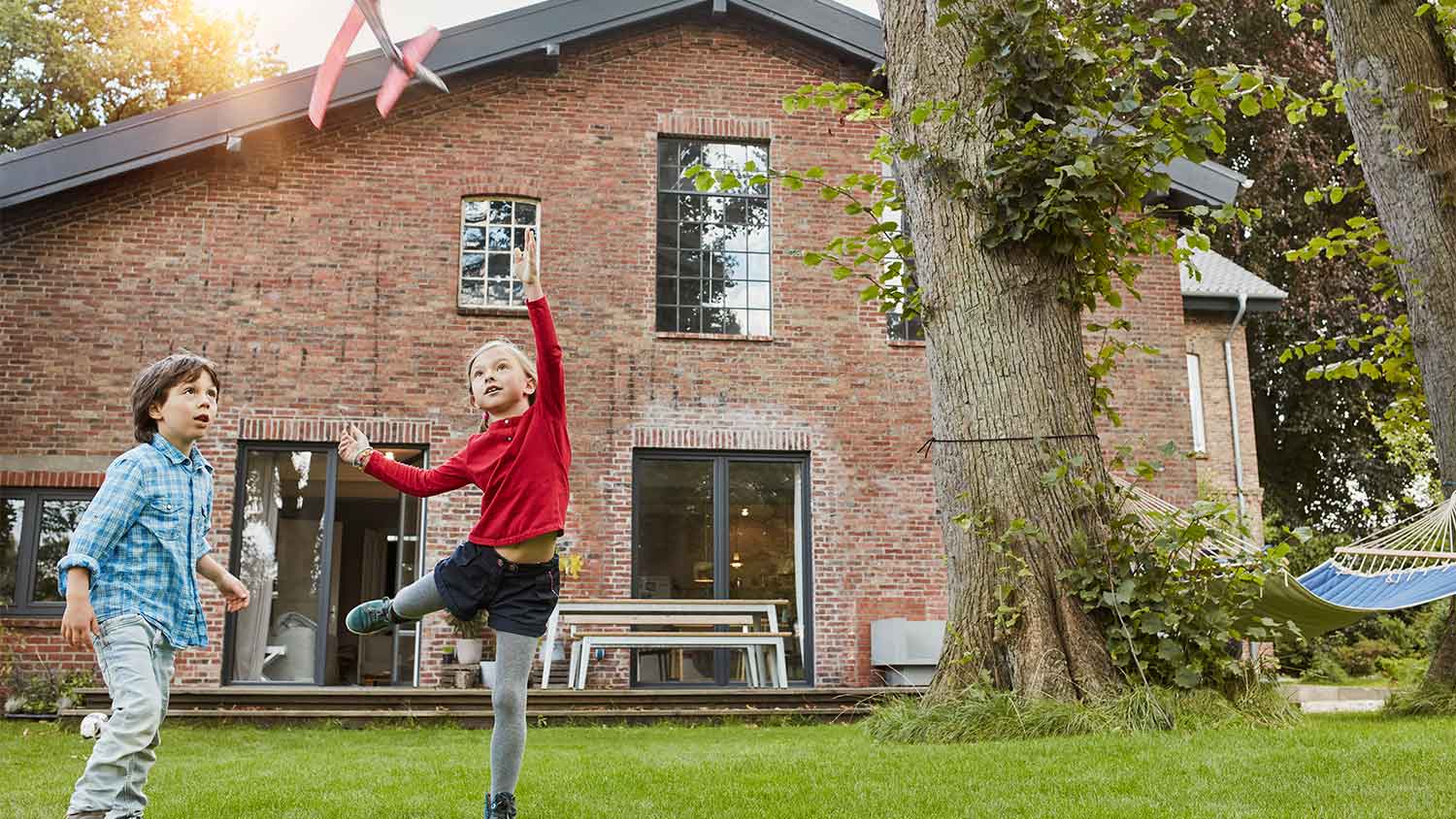 Children play in front of a brick house