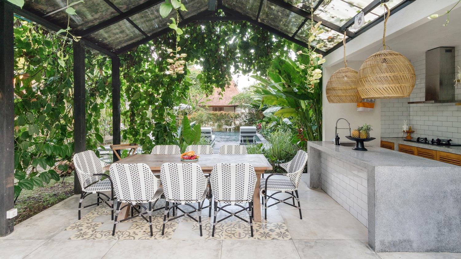 A dining table and chairs in an outdoor kitchen