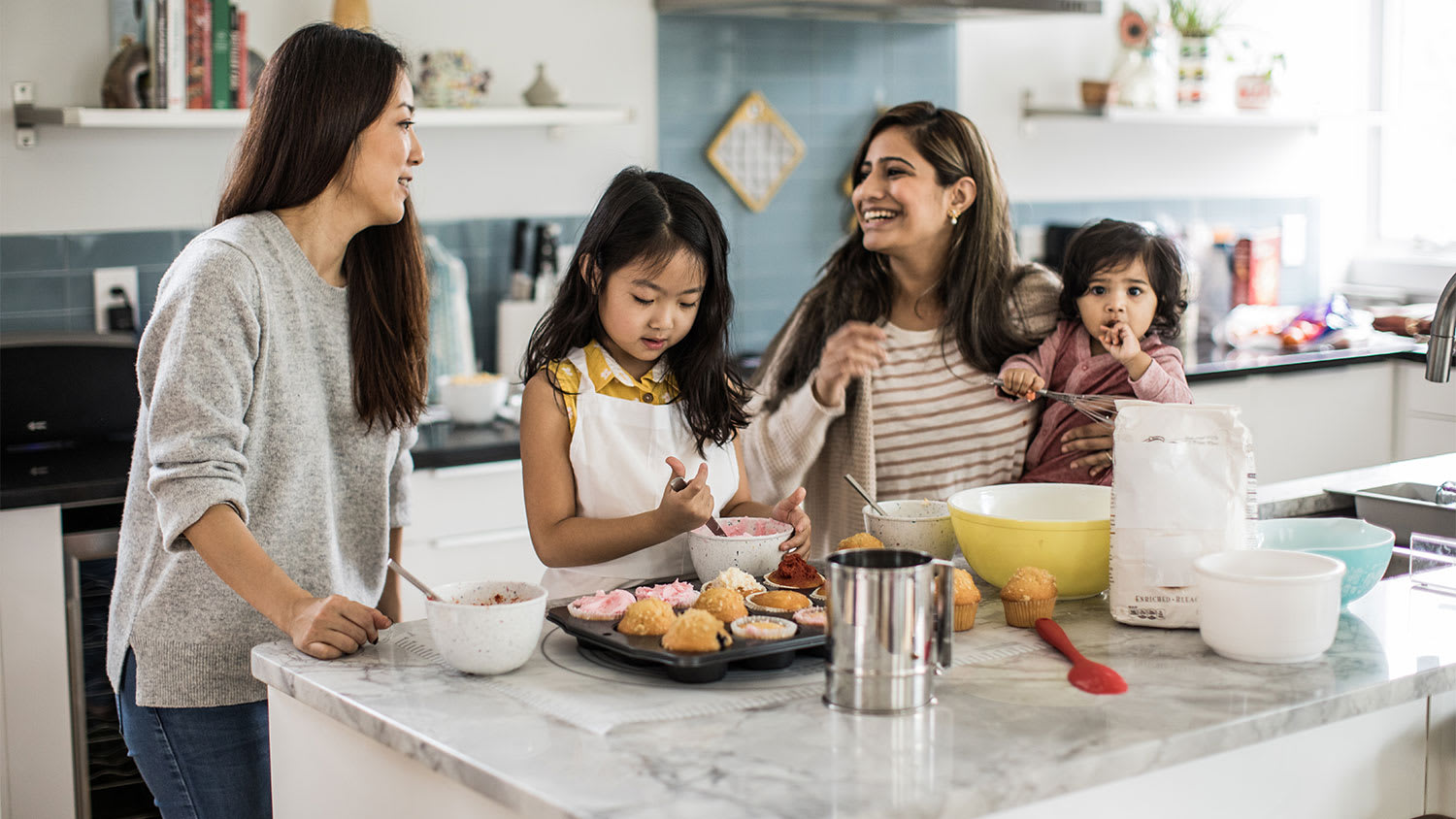 Two mothers and children cooking in a kitchen