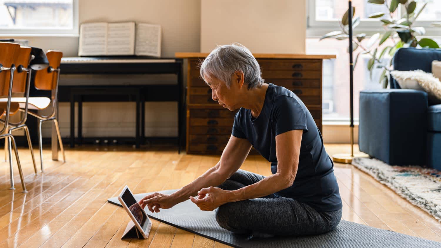 A senior woman doing an online yoga lesson at home