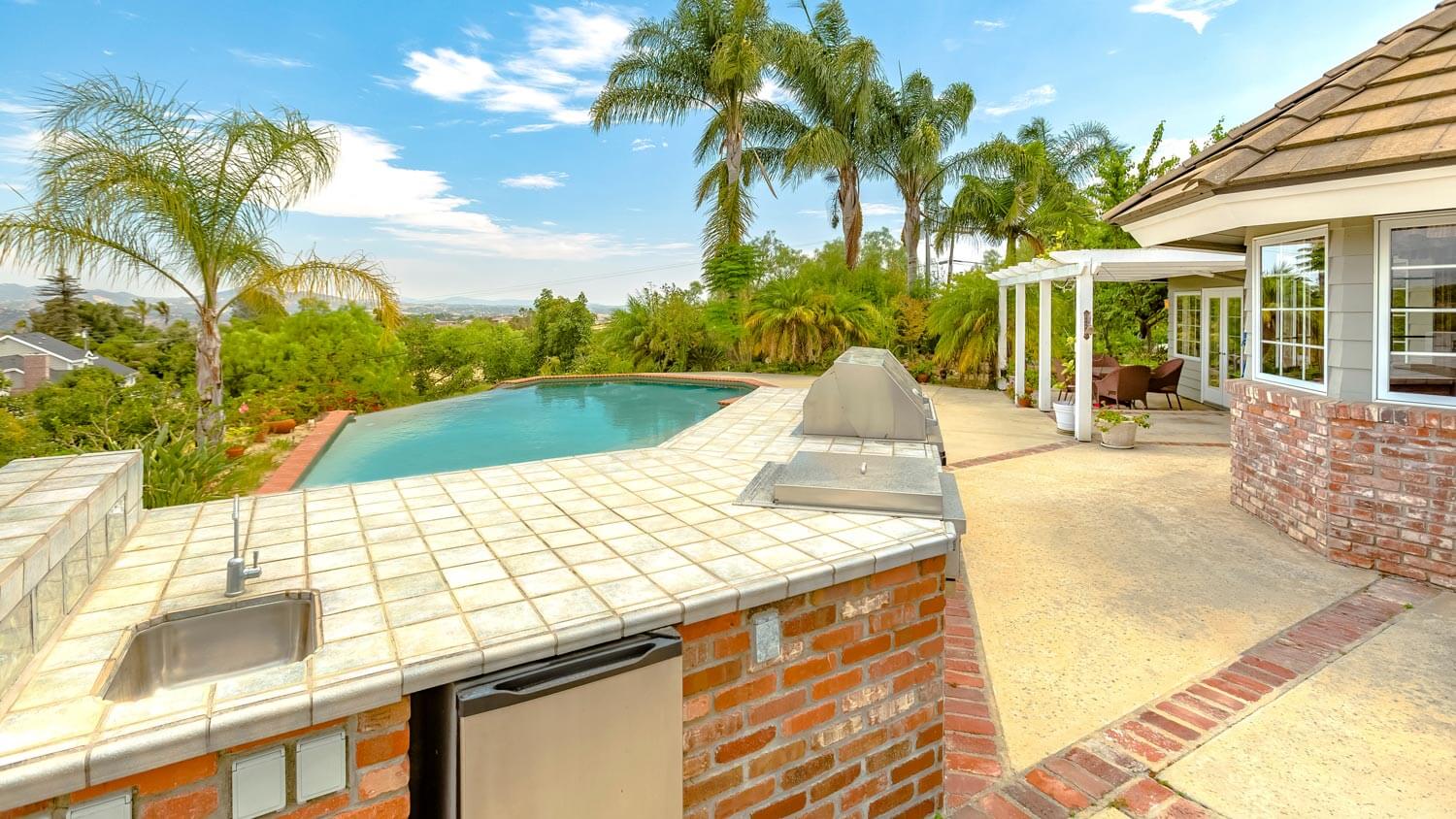 A large pool with an outdoor kitchen and a refrigerator