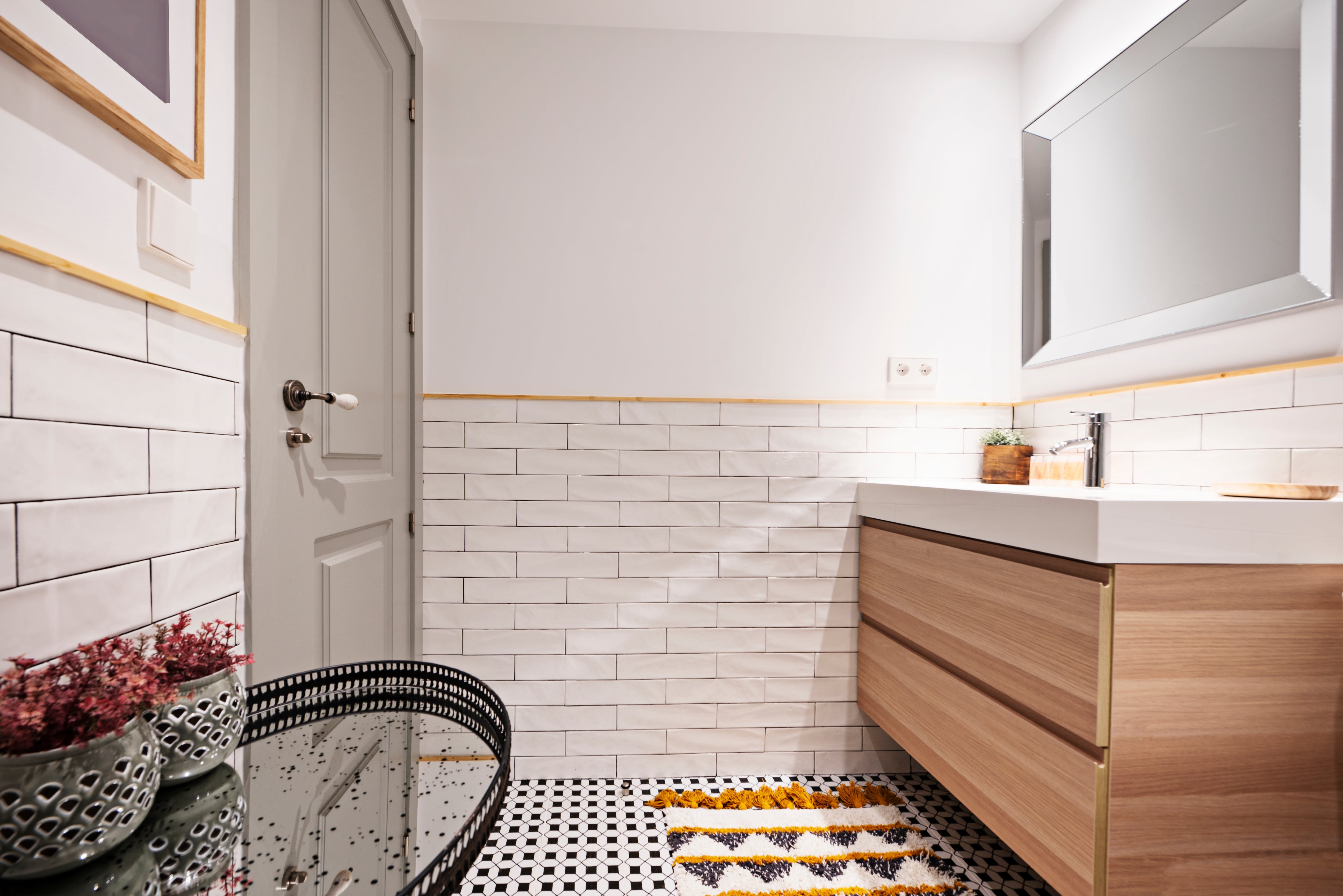 Small bathroom with subway tile backsplash, wooden vanity, and beveled mirror