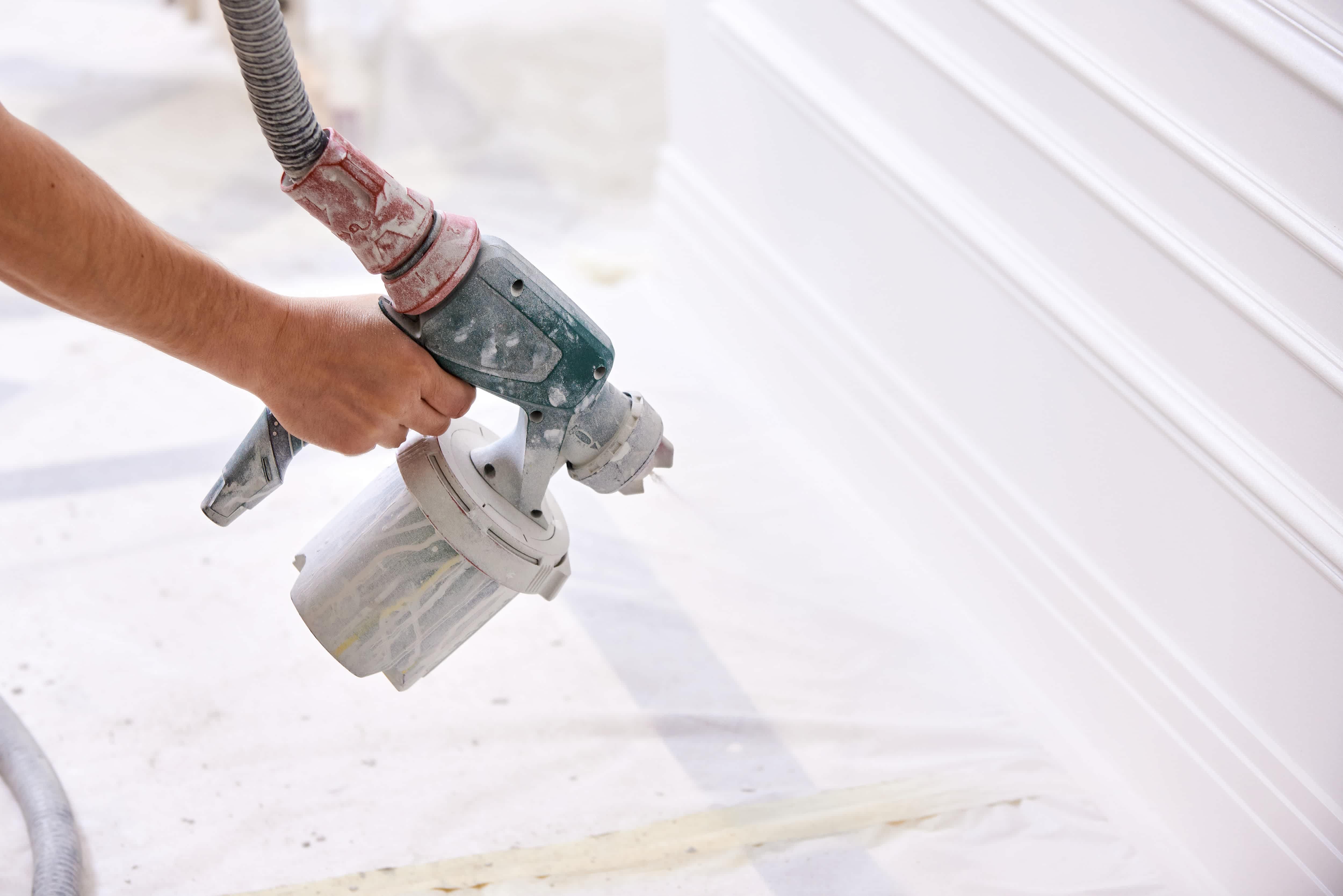 Man testing paint sprayer on wall