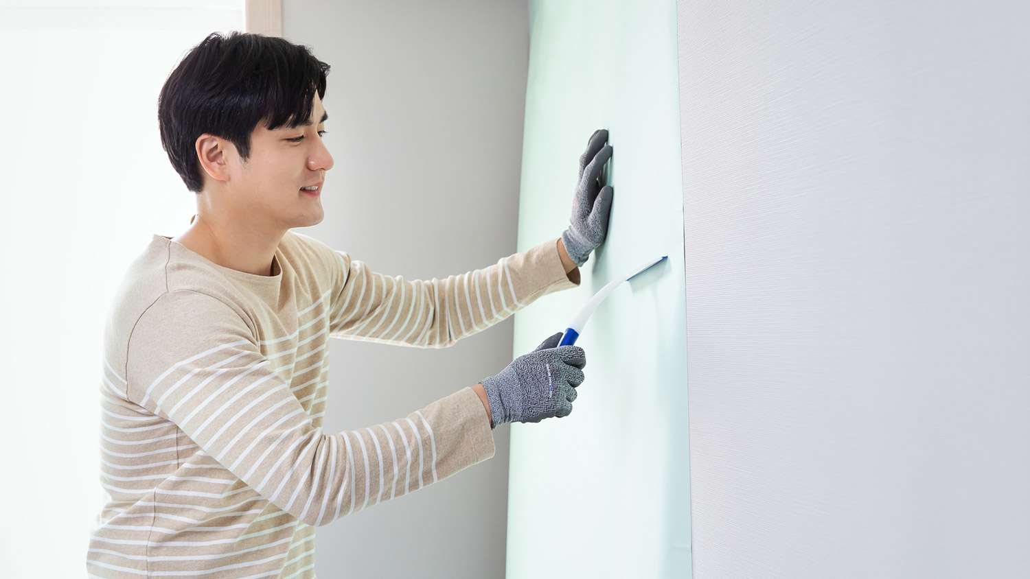 A man hanging new wallpaper