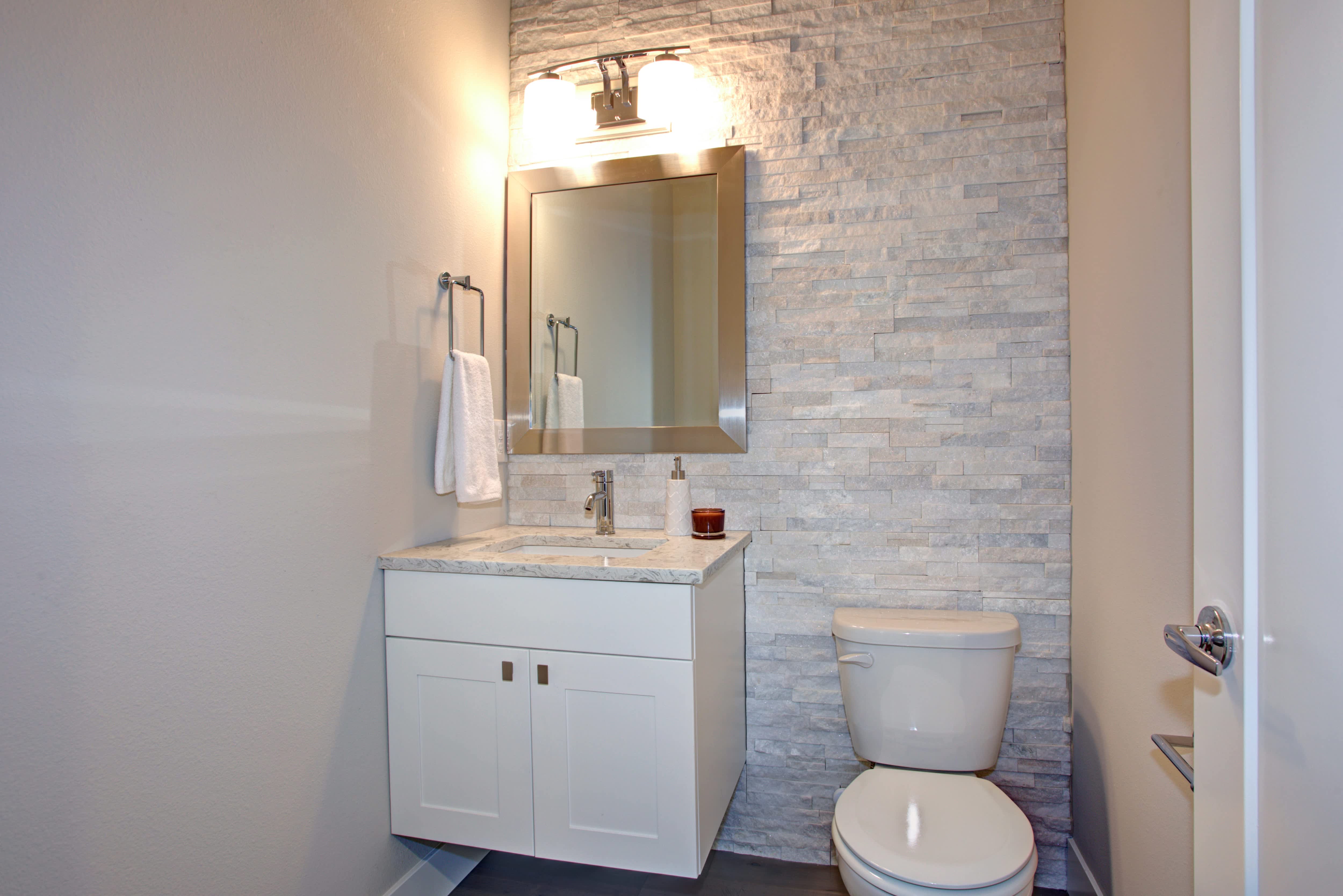 Small bathroom with stacked textured tile, a floating vanity, and a rectangular silver mirror
