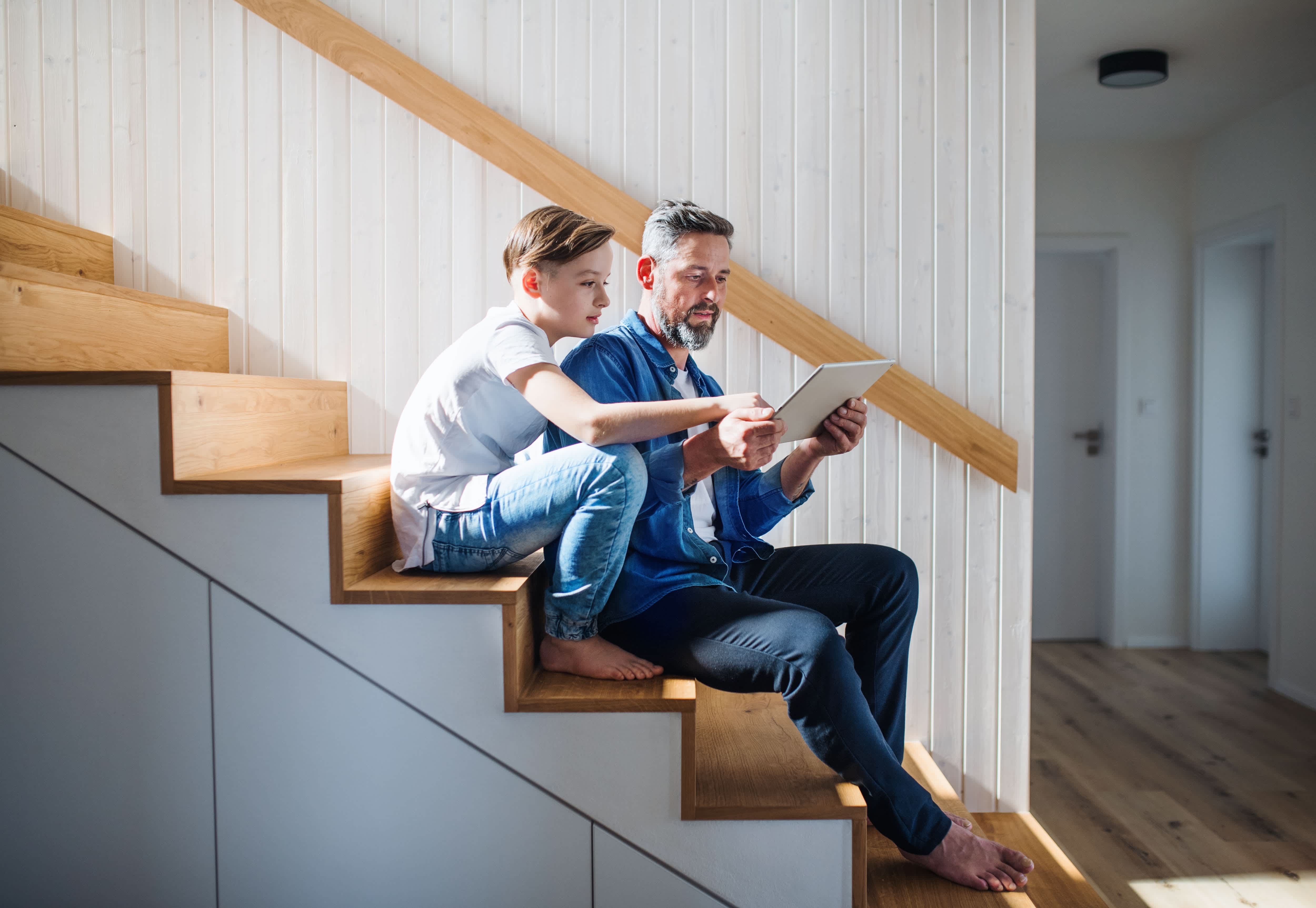 Father and son sitting on wooden staircase in front of shiplap wall