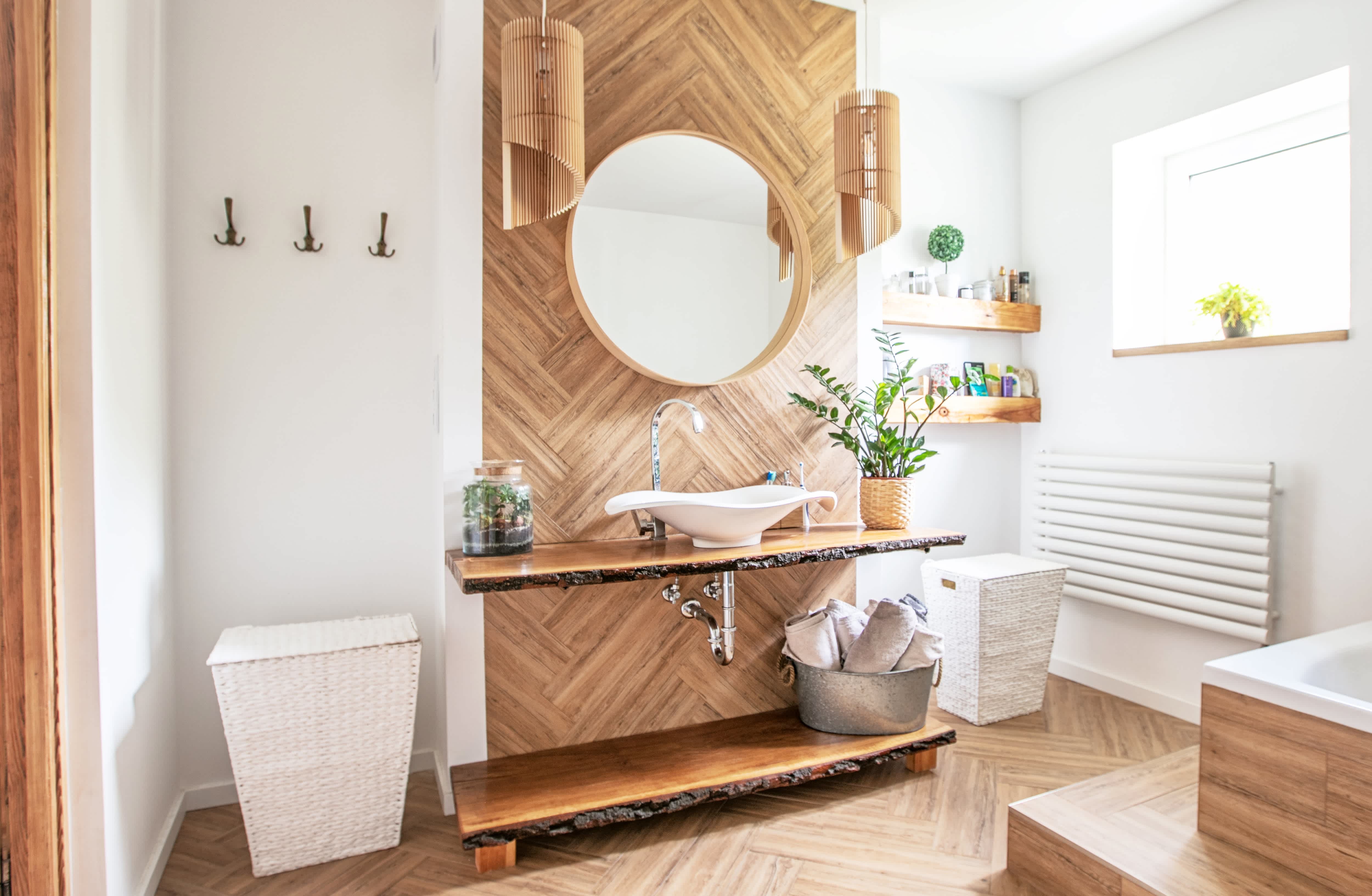 Bright bohemian bathroom with wood panel backsplash, a round mirror, and a sculptural sink