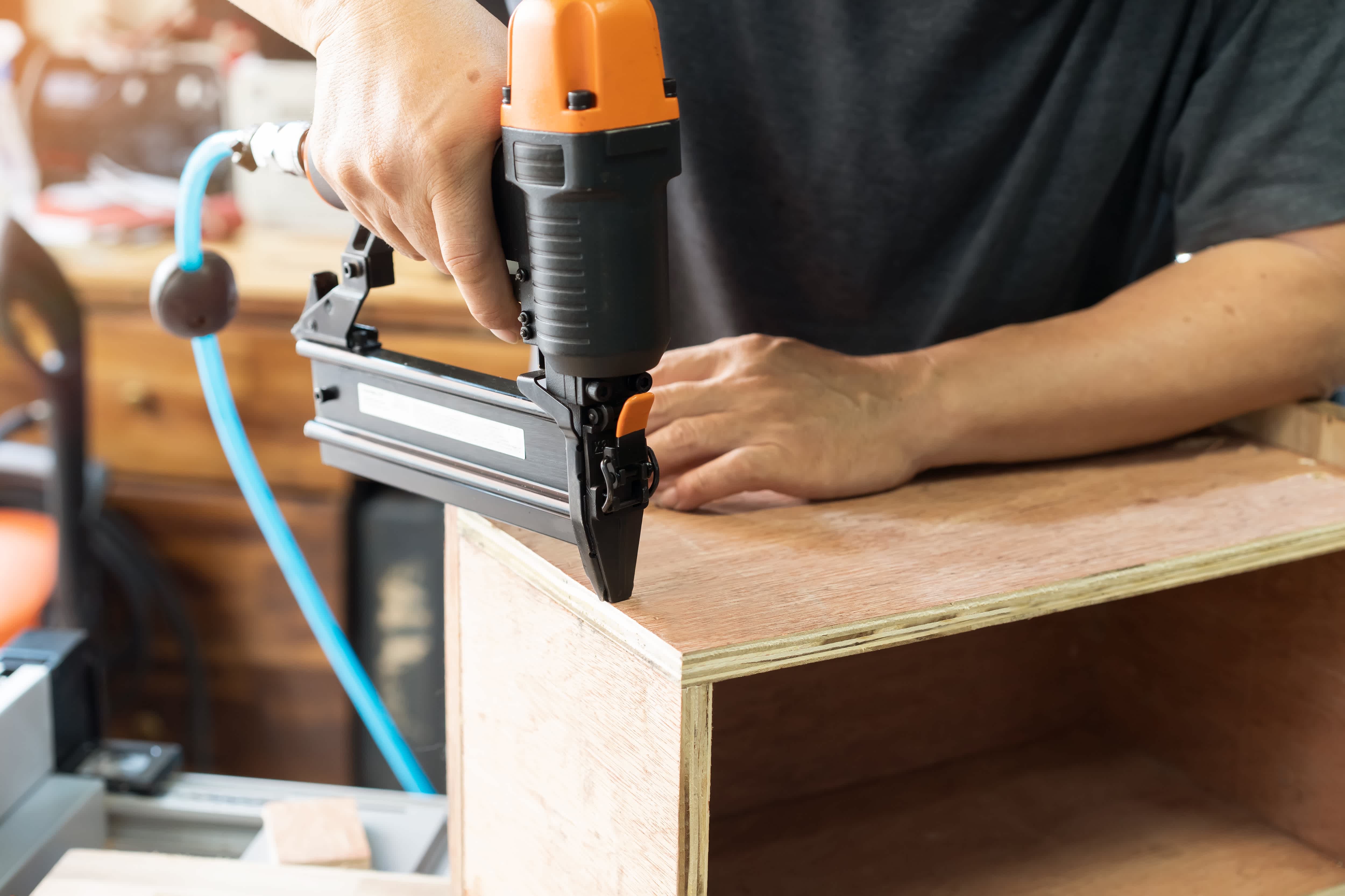 Carpenter using brad nailer to attach pieces of wood together