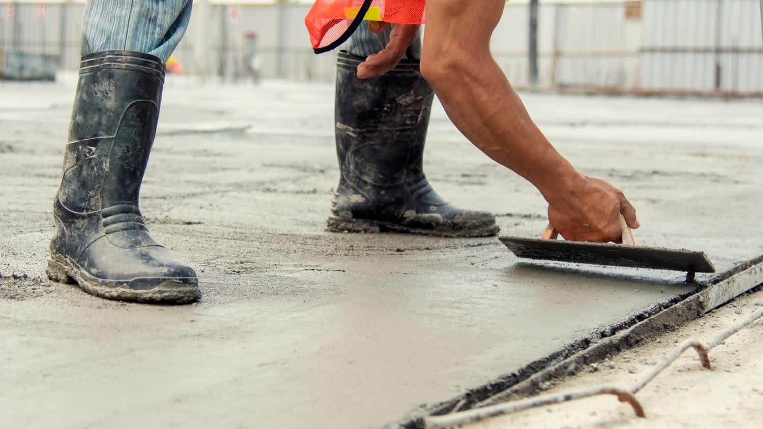 A worker leveling poured concrete with a trowel