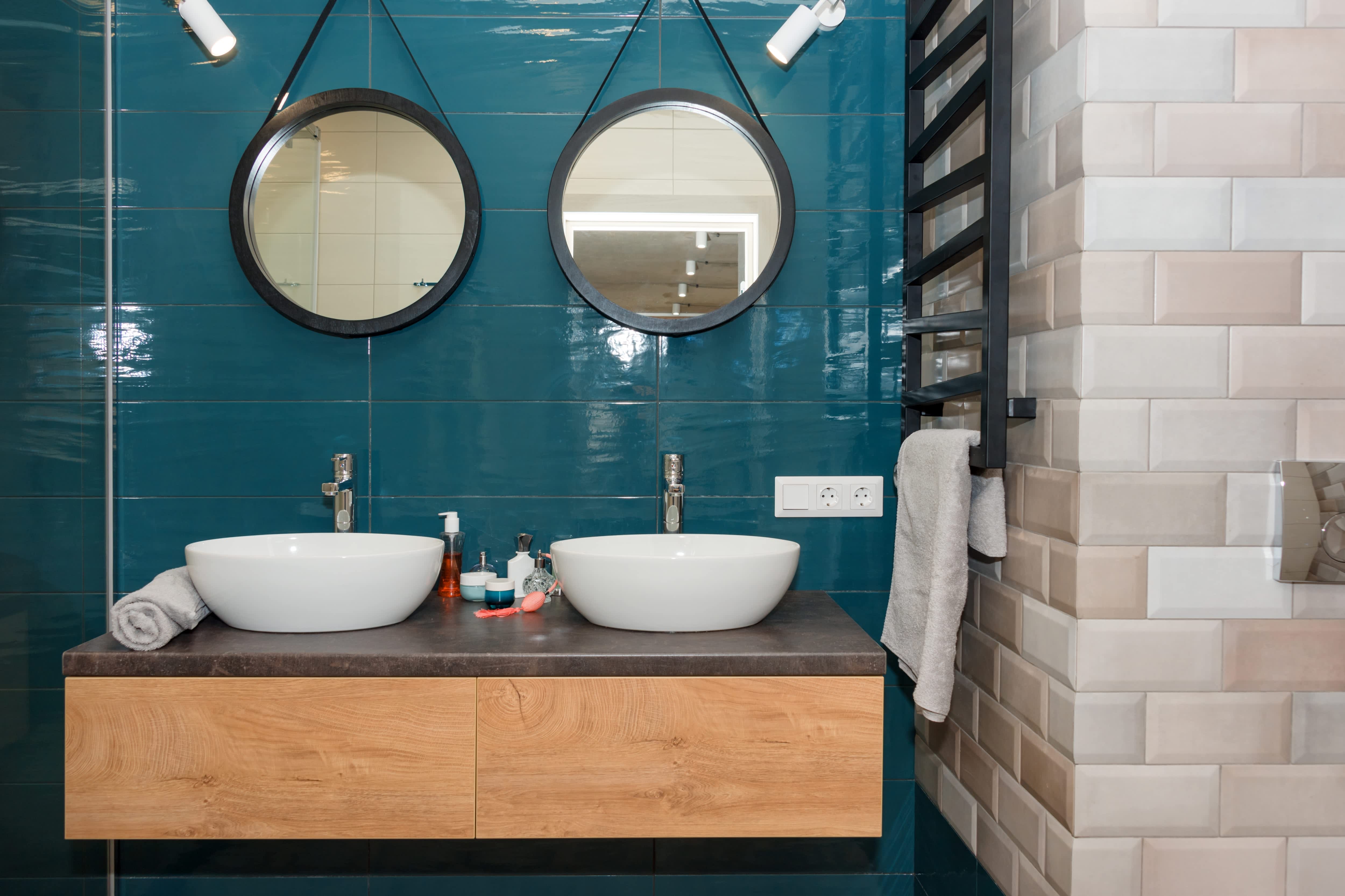 Modern bathroom with two round mirrors, two white vessel sinks, and a floating wooden vanity