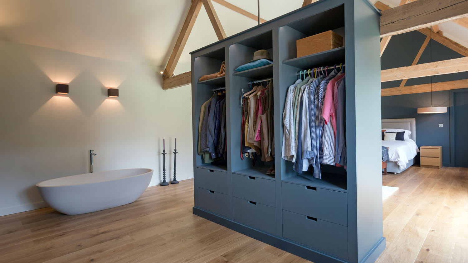 A closet and a bathtub in an open-space modern bedroom
