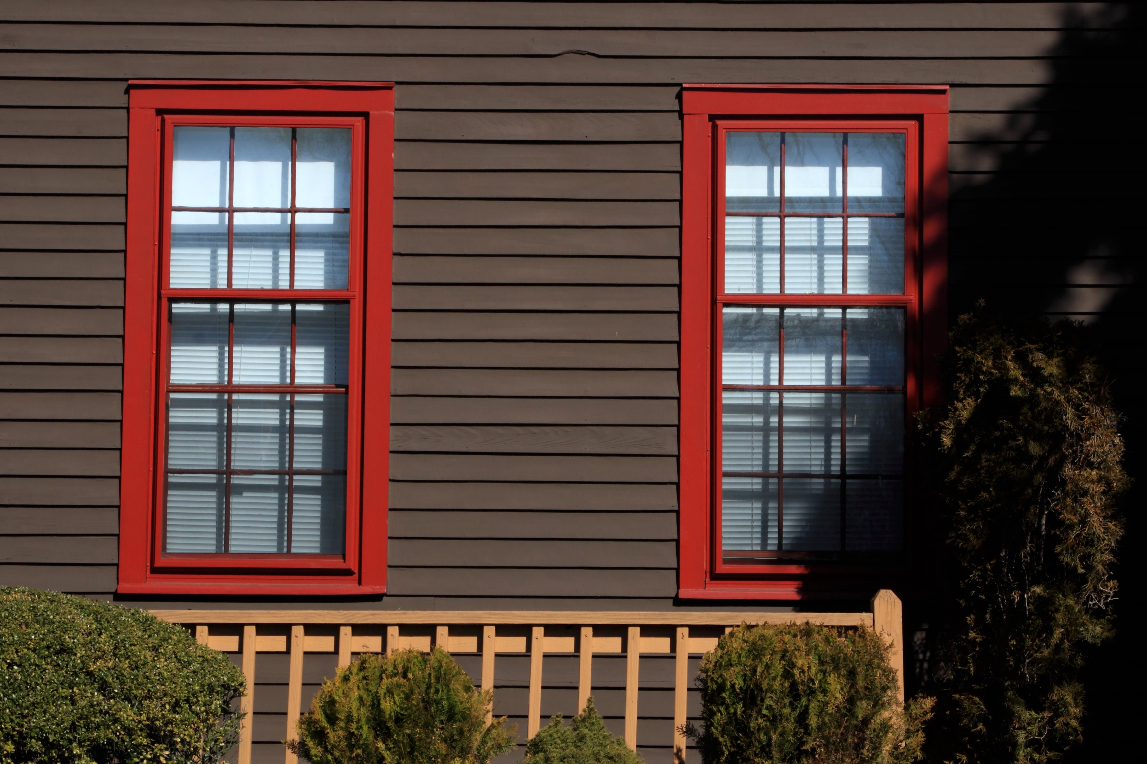 Home with dark brown vinyl siding and red window trim