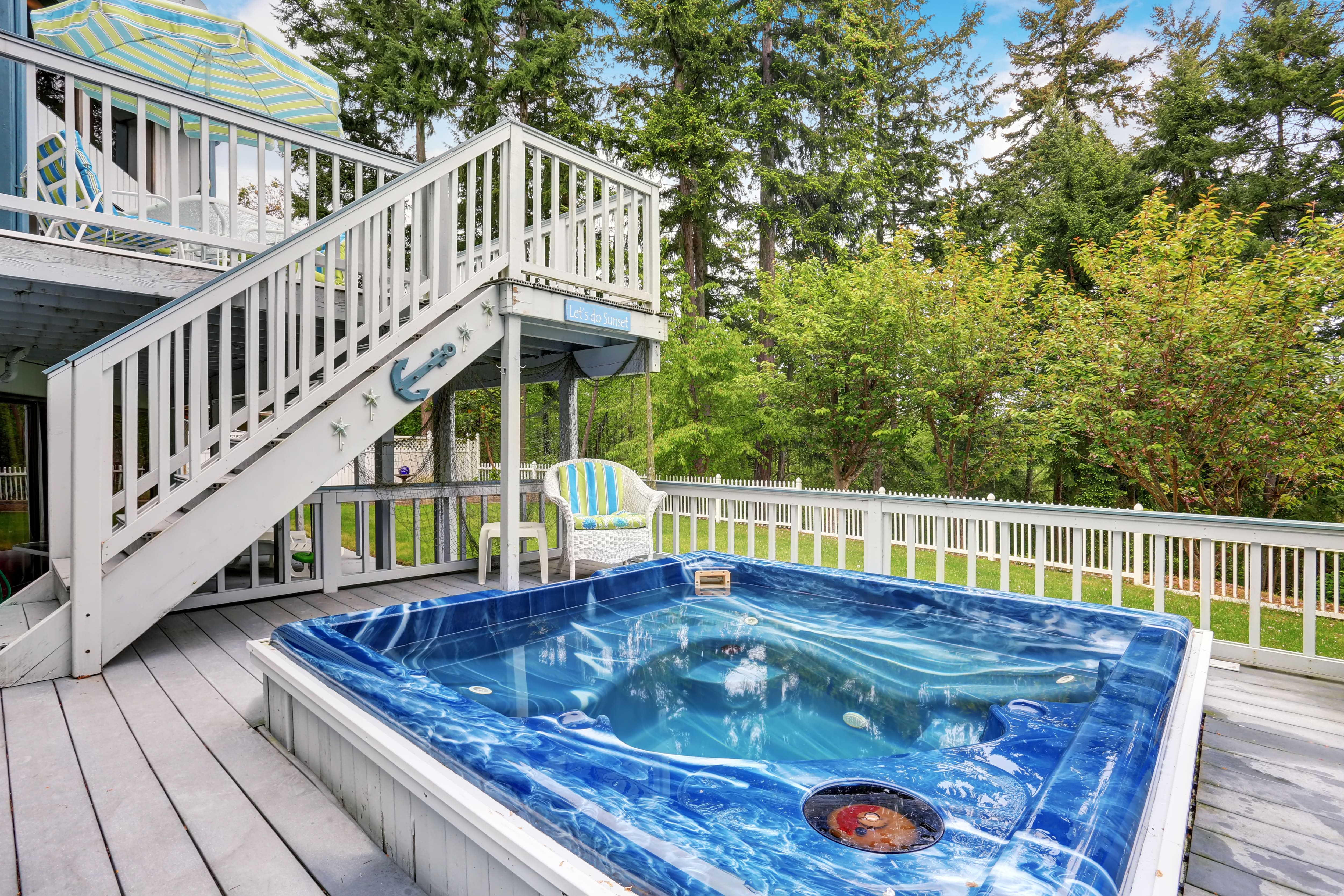A deck with an upper and lower level with a hot tub on the lower section
