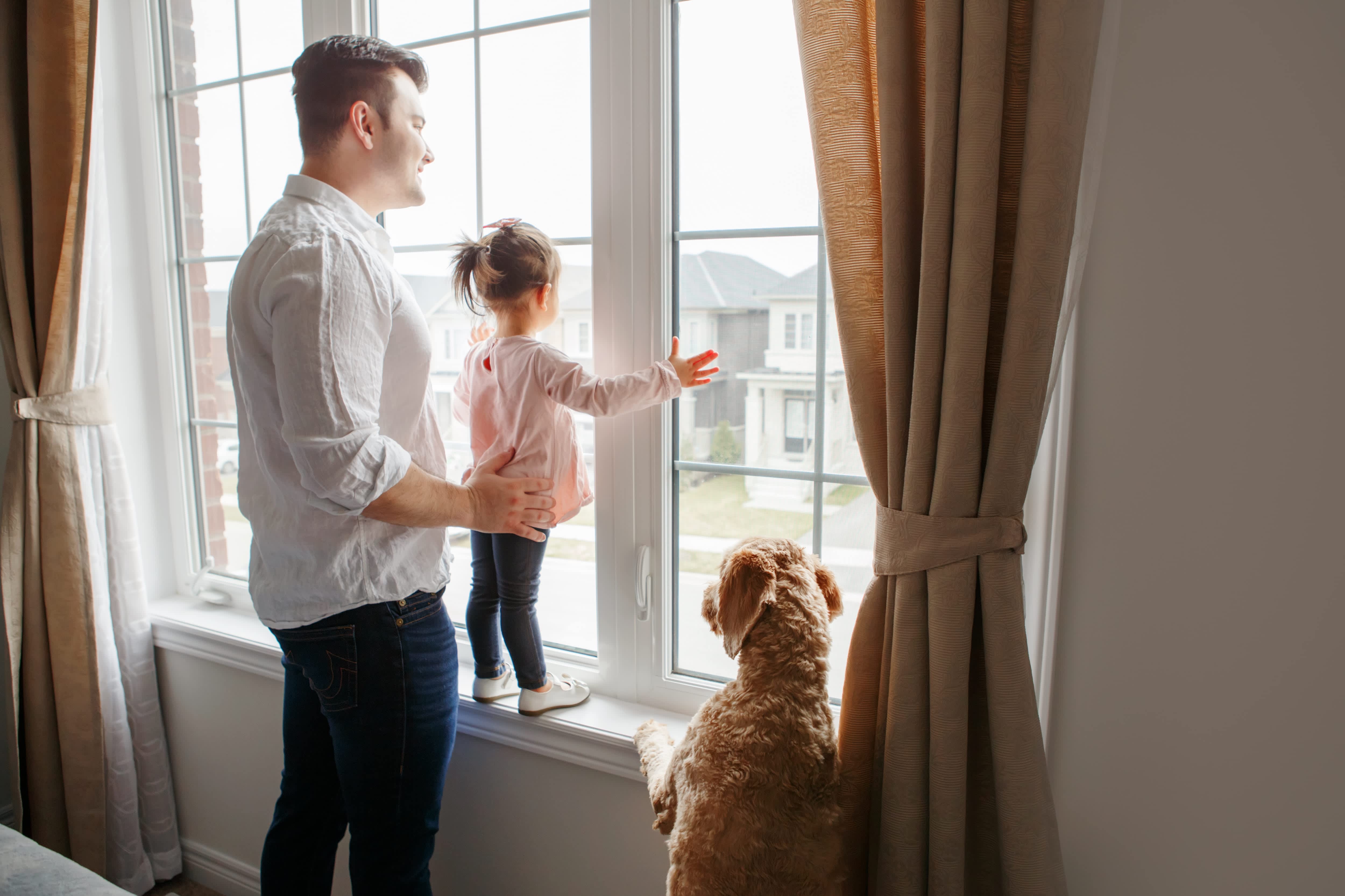 Father and daughter looking out of new window