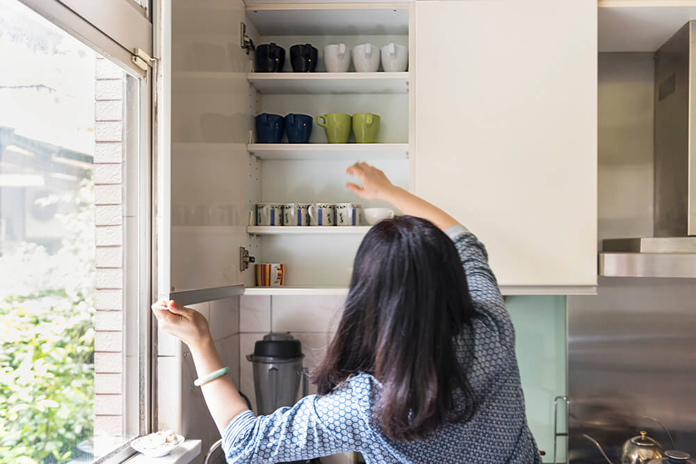 Person getting a cup down from an upper cabinet