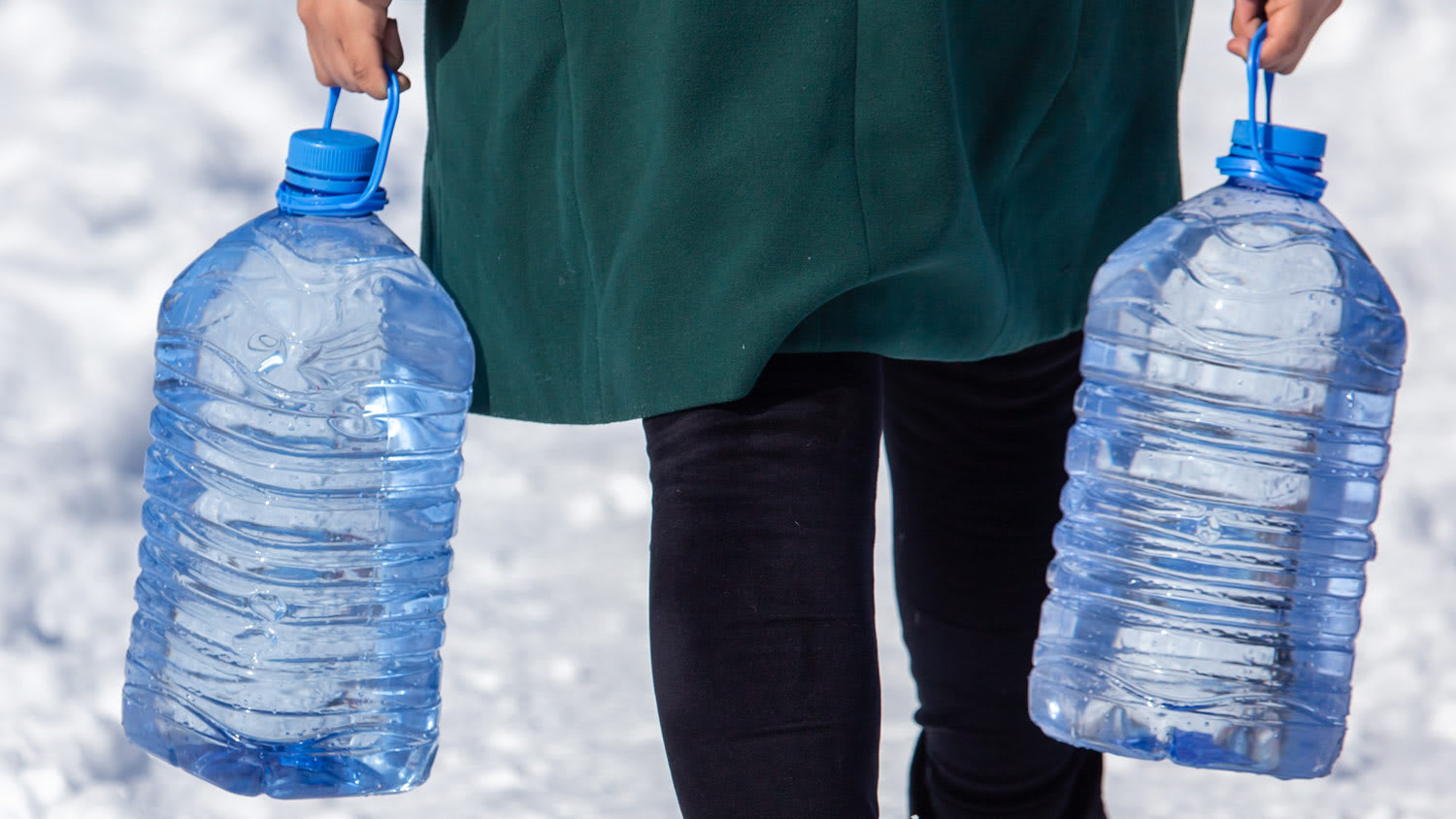 A woman carrying water in plastic bottles