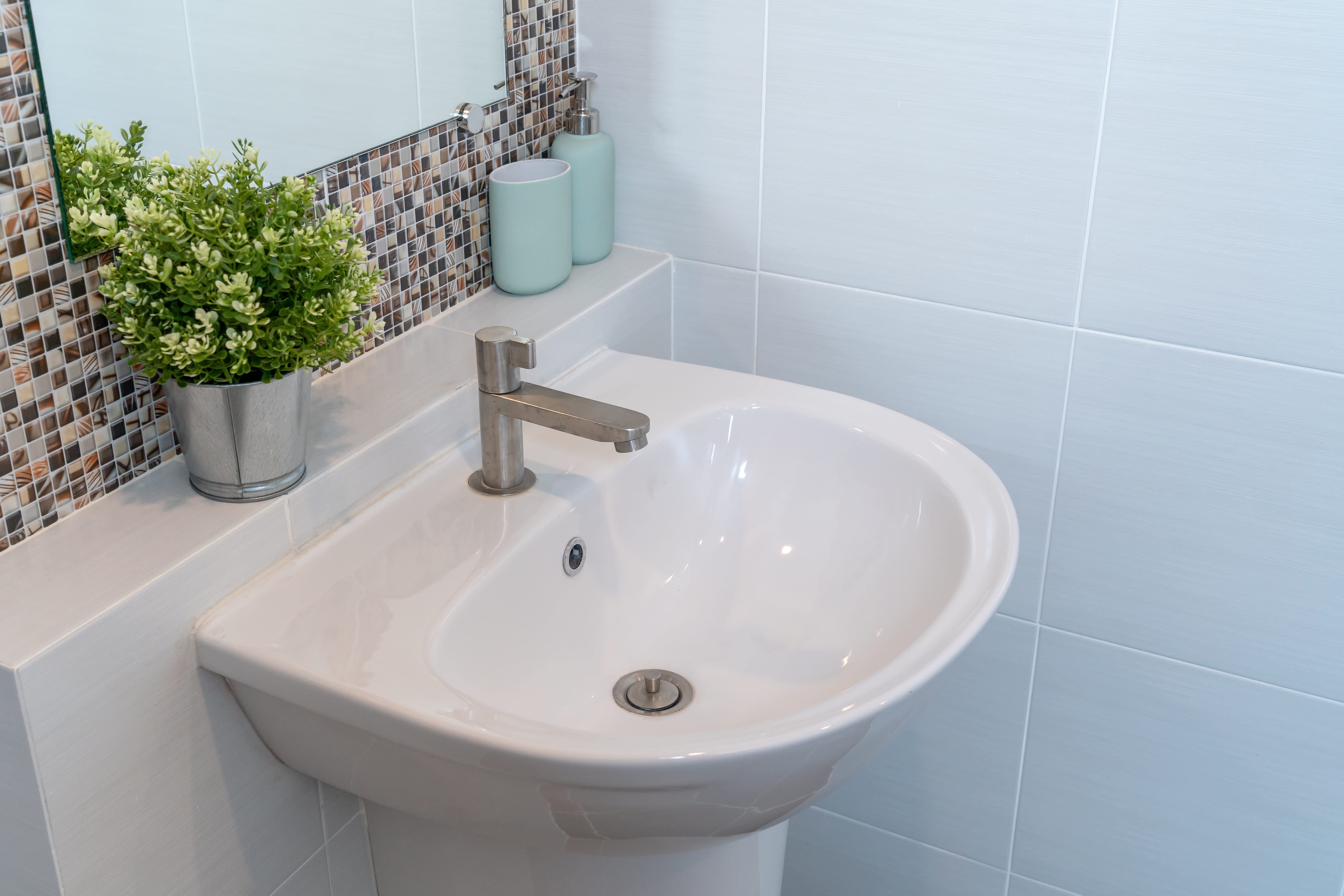 Small bathroom with white tile walls and a glass tile backsplash