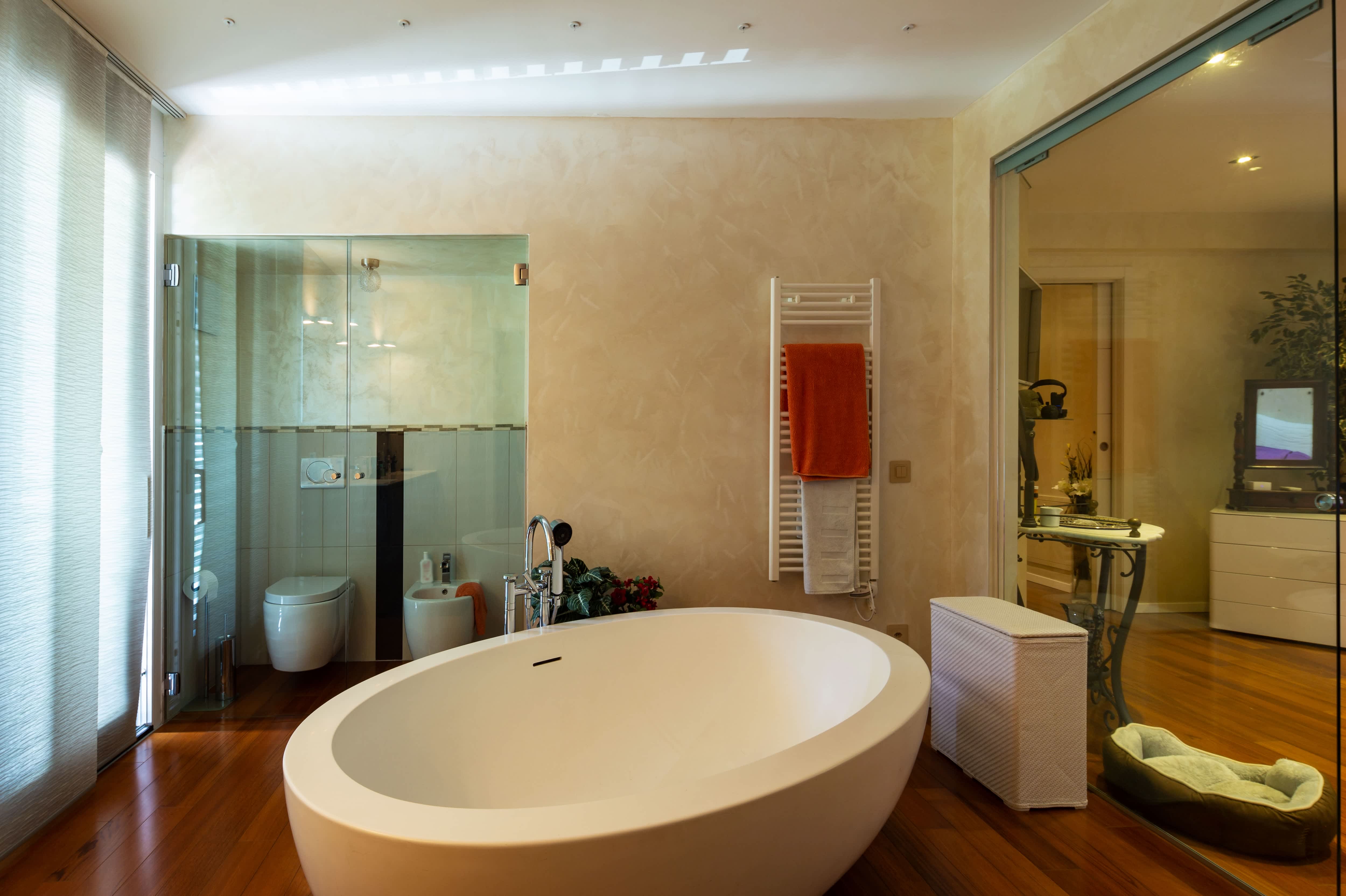 Modern bathroom with wooden floors, a white bathtub, and textured wallpaper