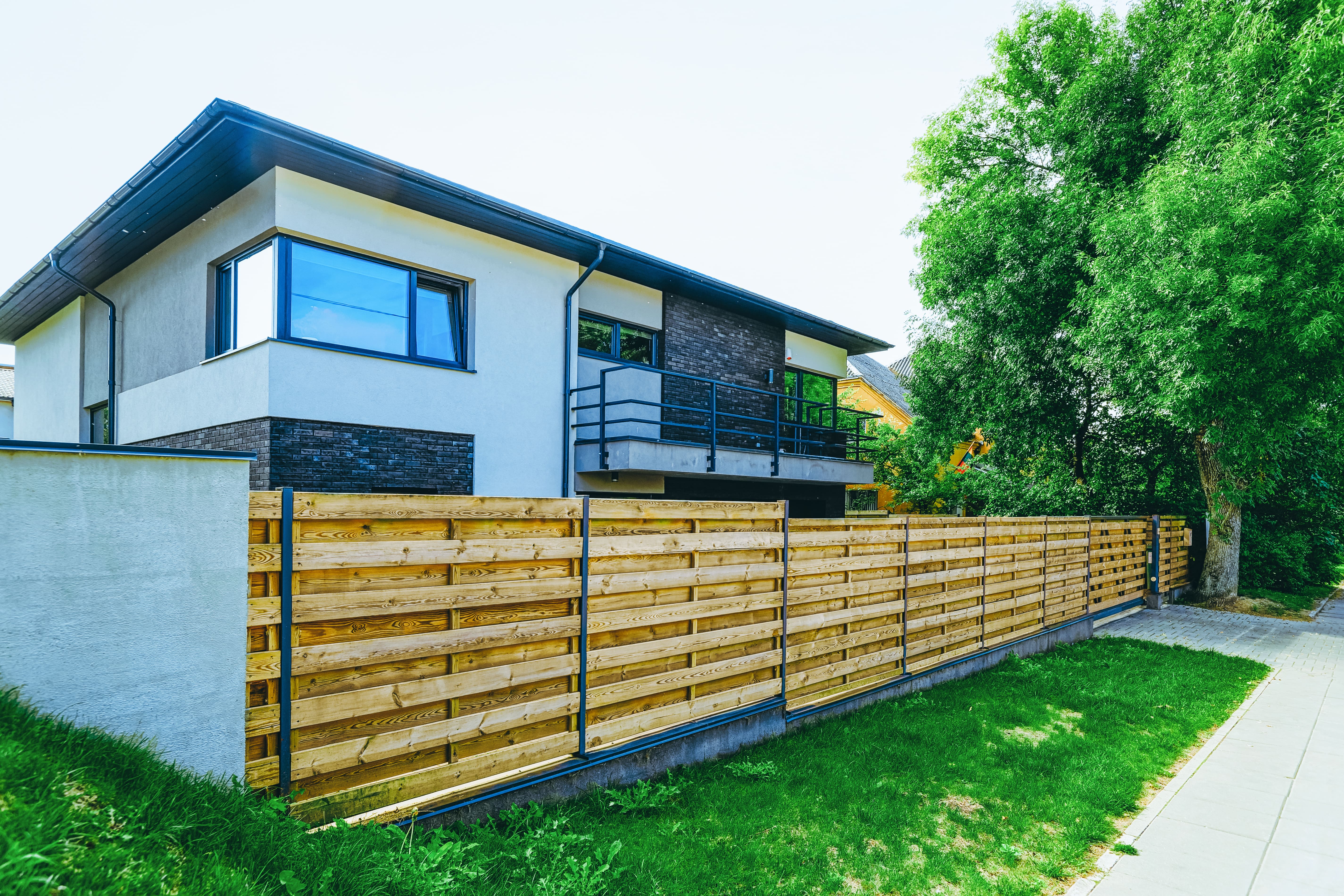 A modern looking home with a wooden horizontal slat fence in the front yard