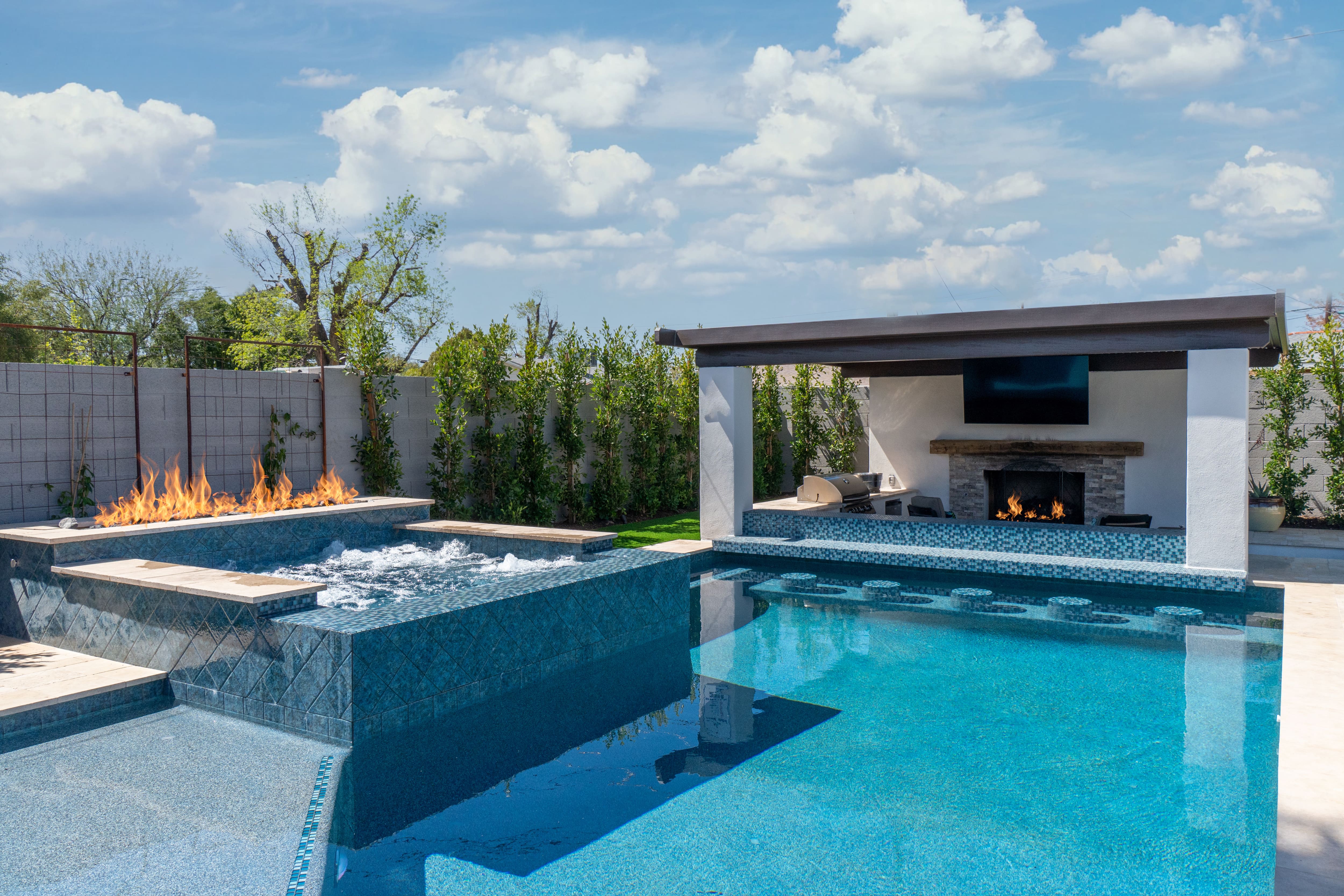 A backyard patio area with a fireplace next to the hot tub
