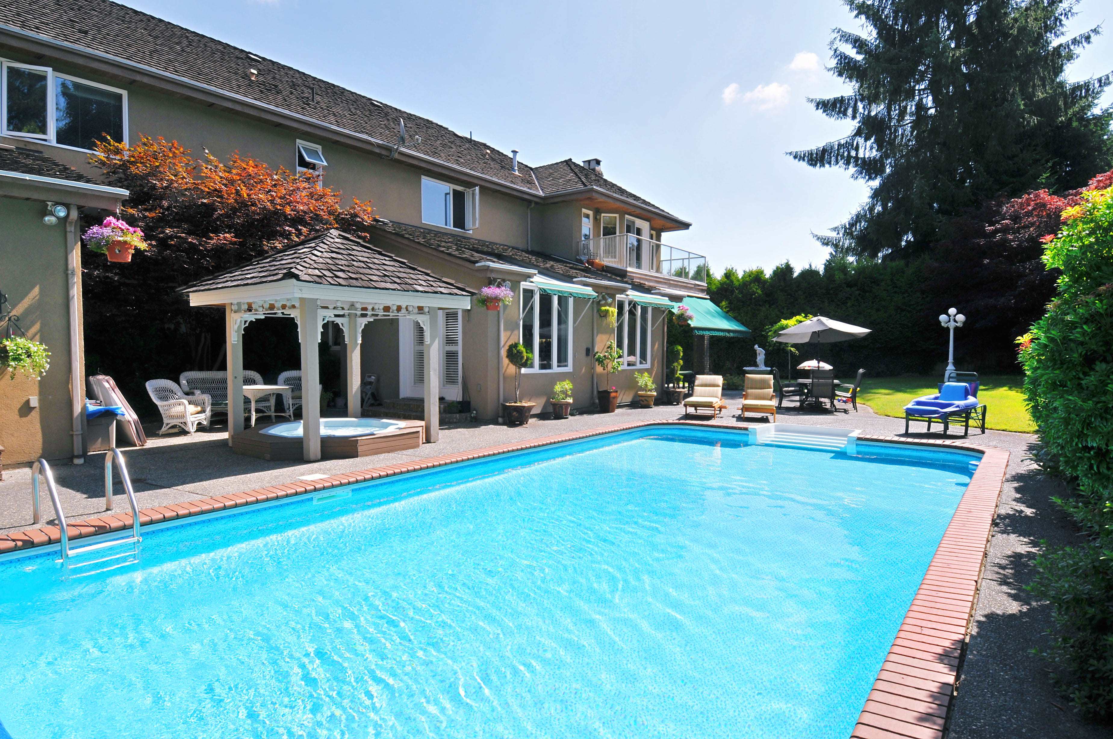 A backyard with a hot tub under a gazebo