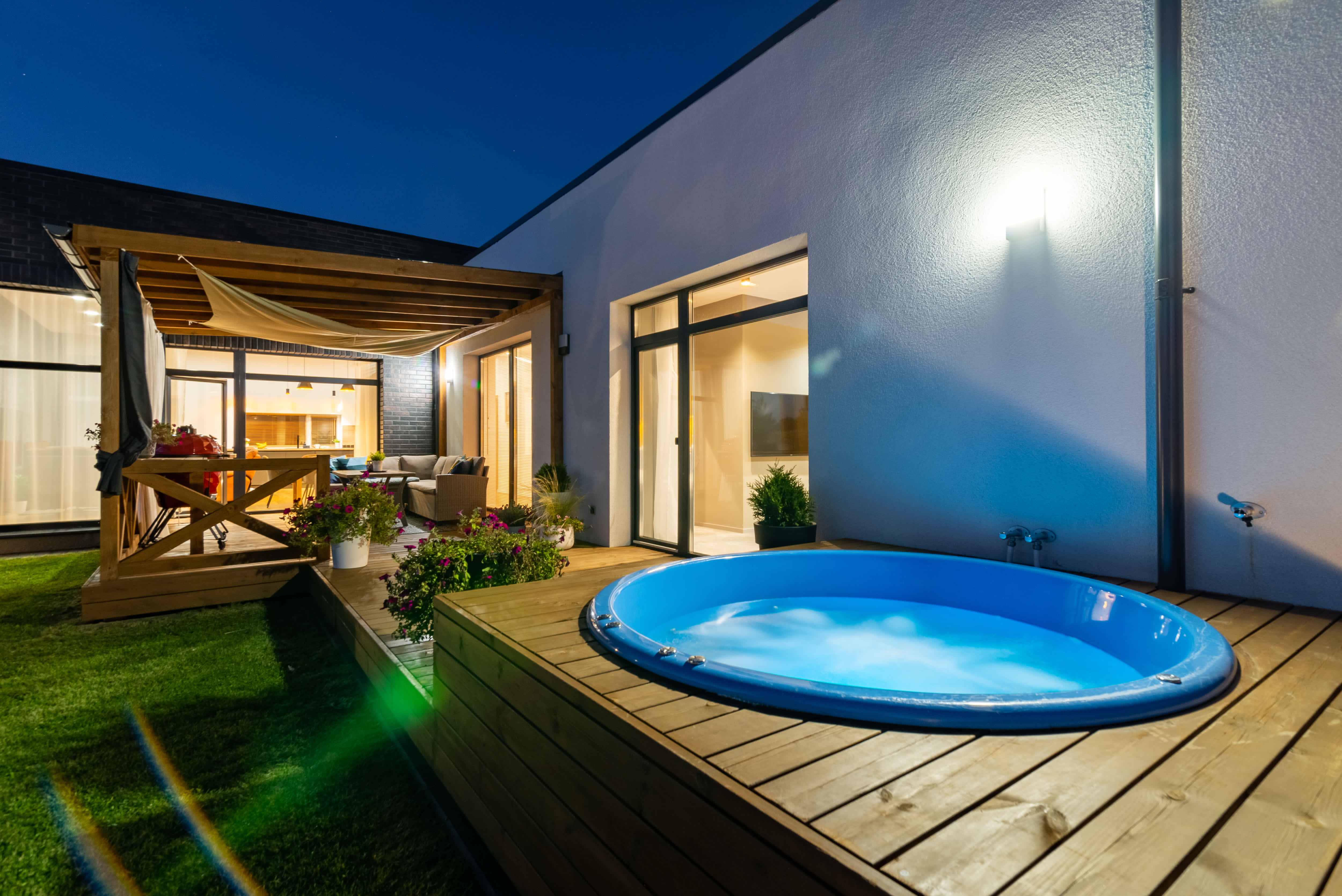 An illuminated hot tub raised up on a platformed section of a deck