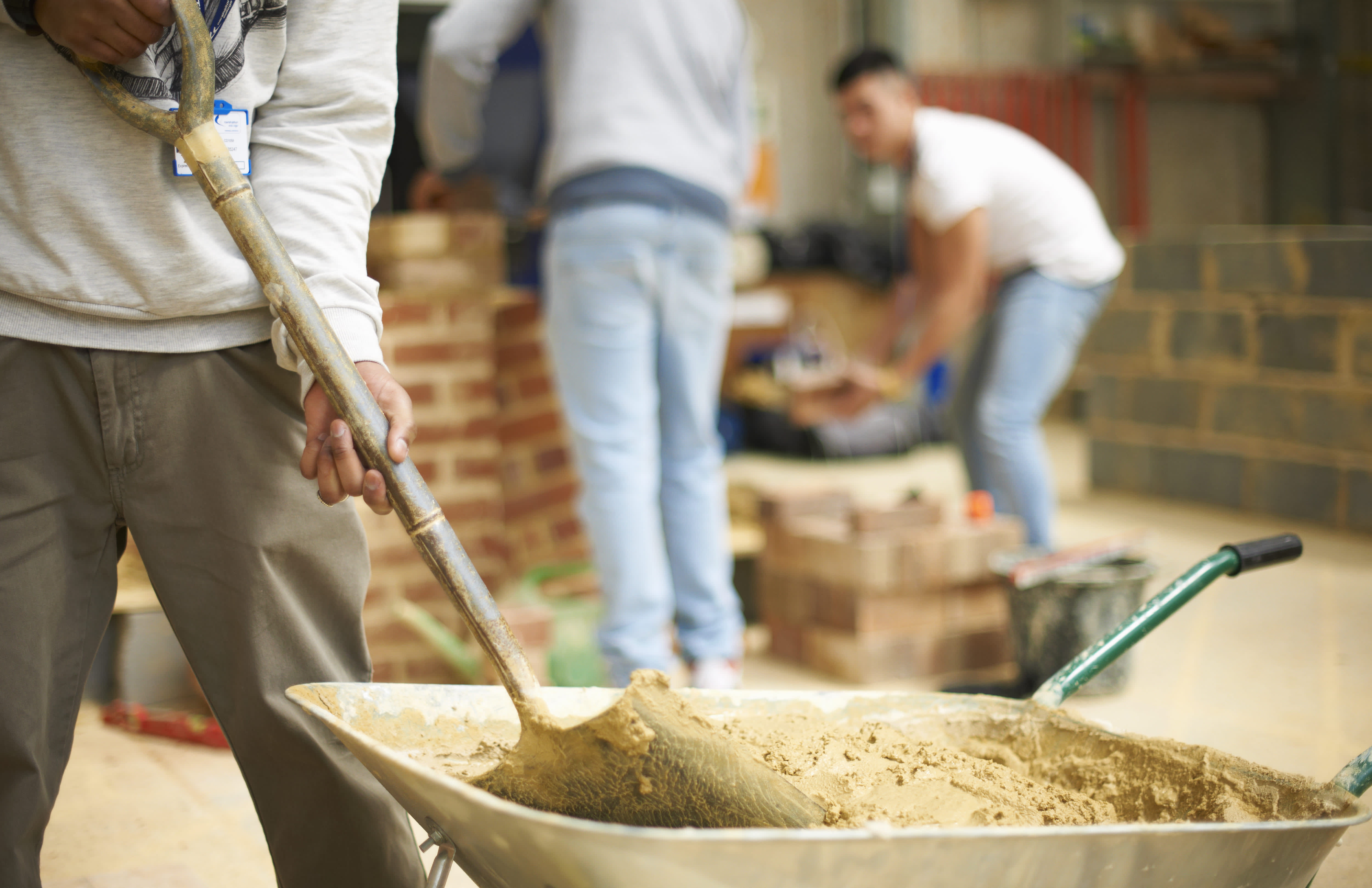 Group of workers mixing concrete in wheelbarrow