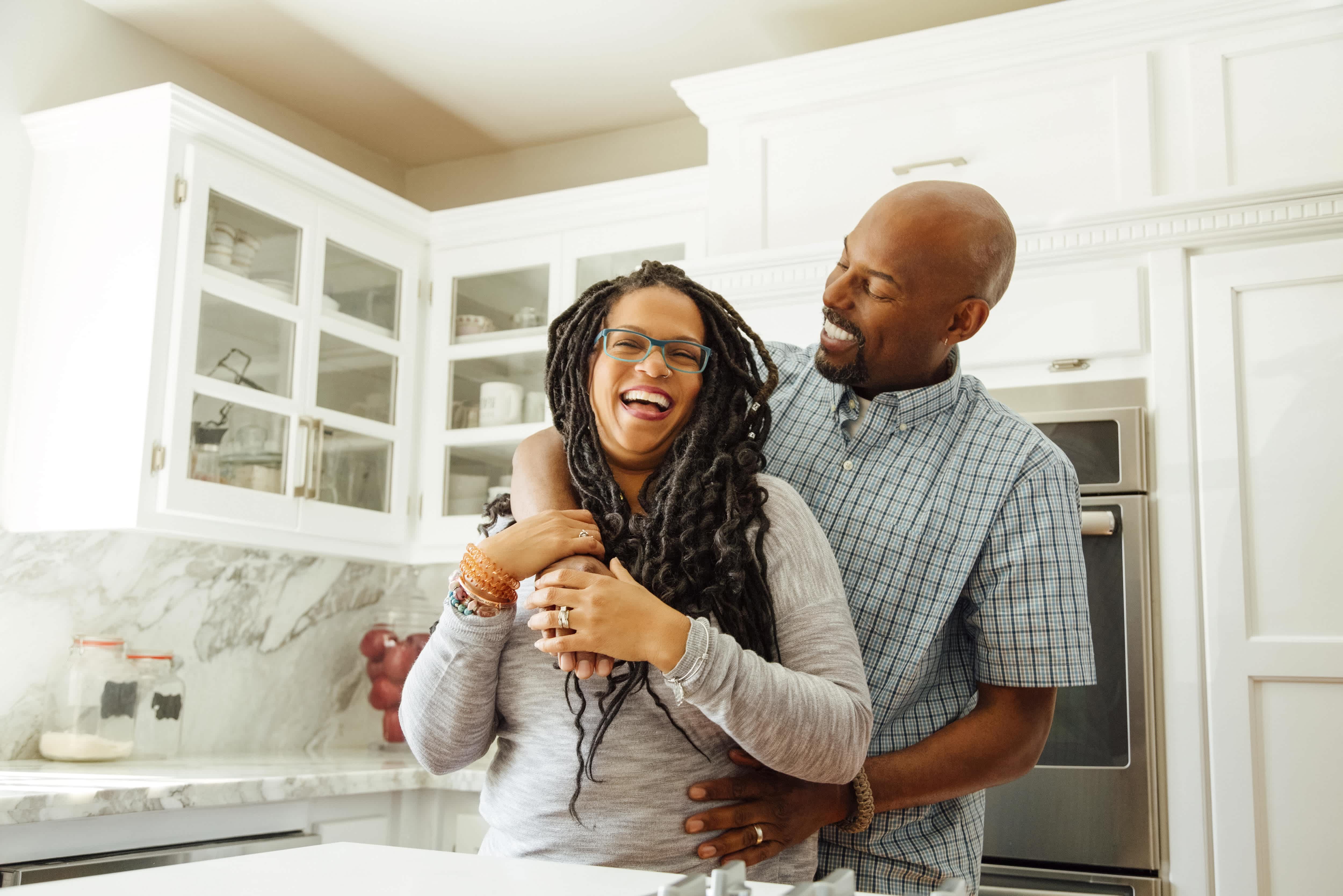 A couple in a white kitchen with marble slab backsplash