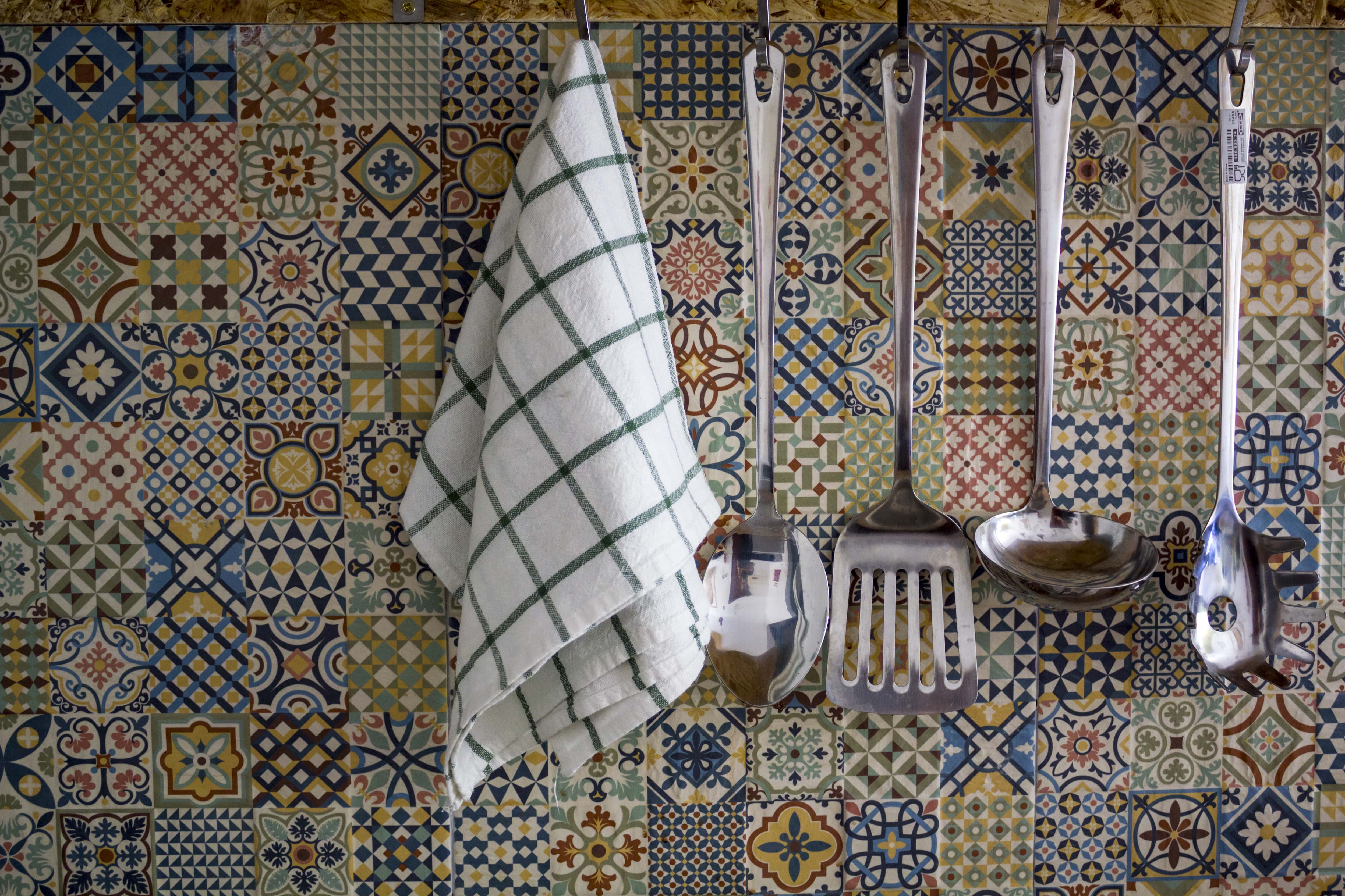 Utensils and a white towel against a mosaic print backsplash